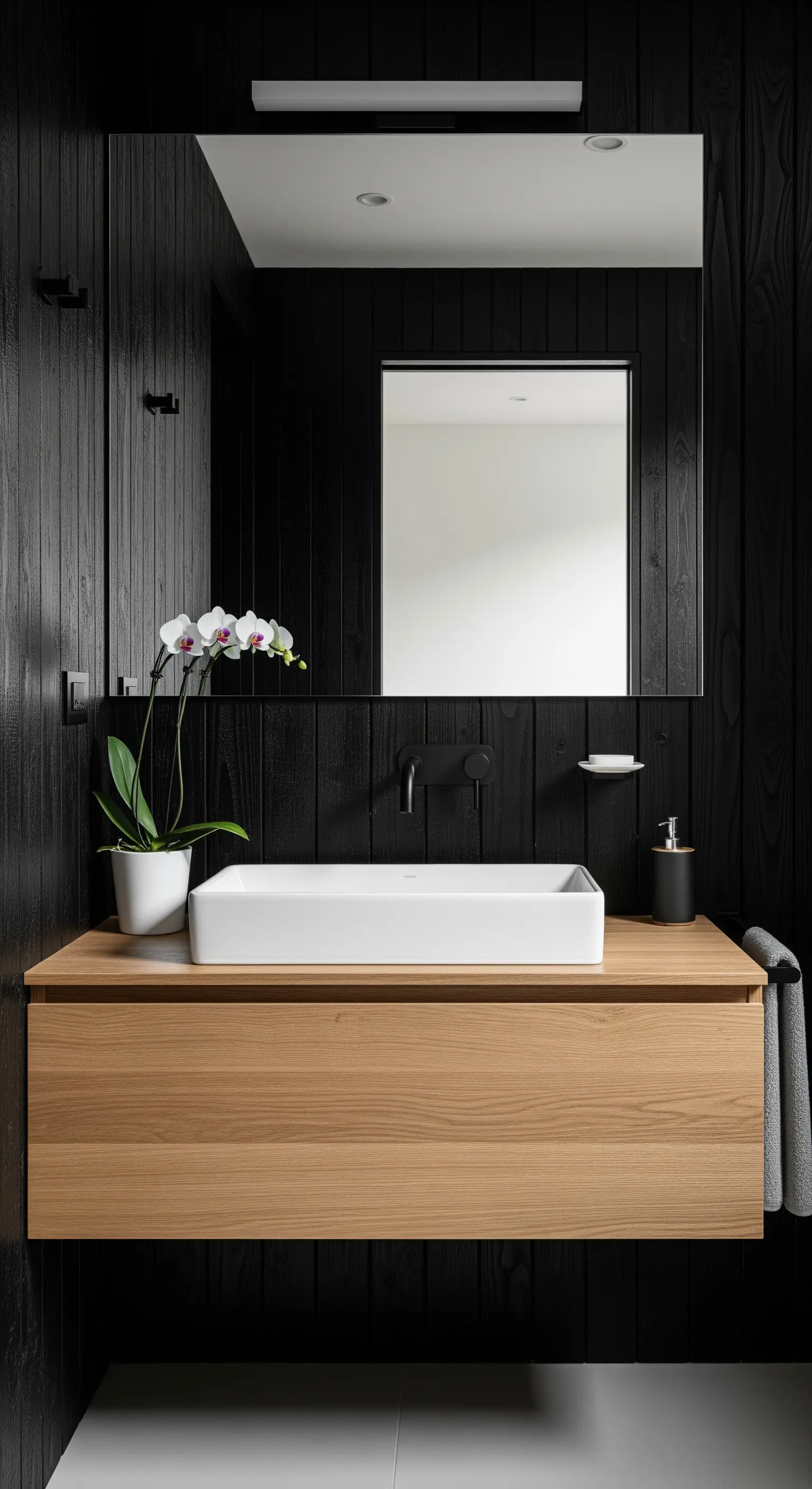 Bagno con pareti in legno nero, mobile in legno chiaro e lavabo bianco.