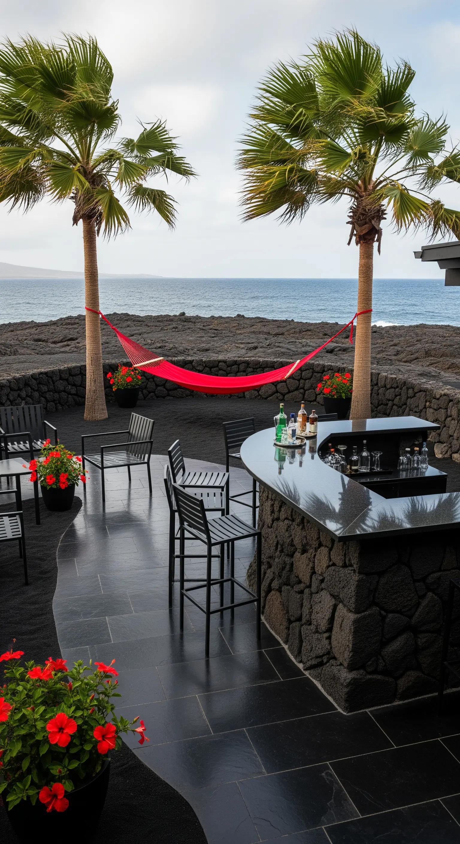 Patio con sabbia nera, bar in roccia lavica, arredi neri e un'amaca rossa.