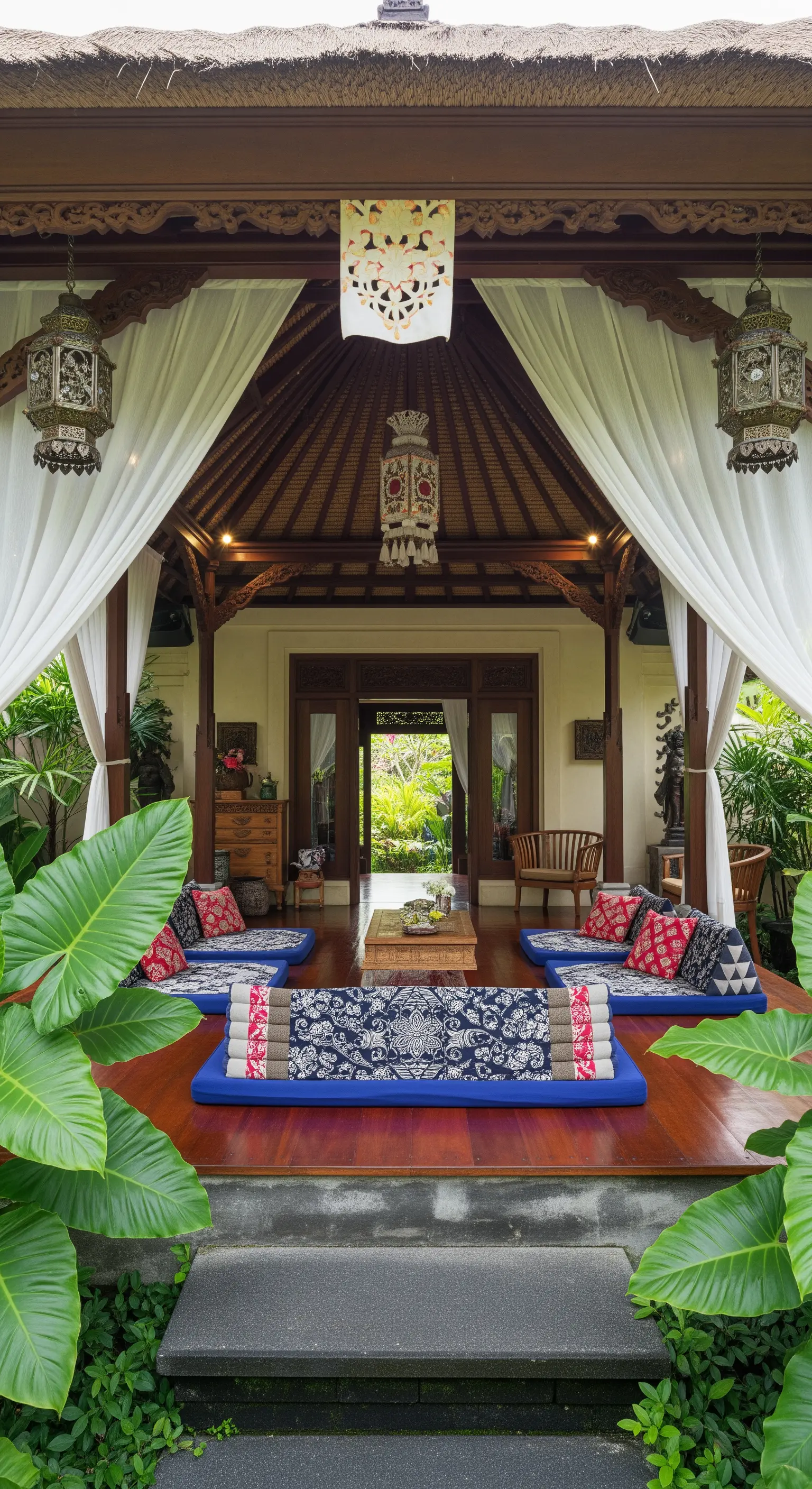 Padiglione balinese con sedute a terra, tessuti tradizionali e tende bianche.