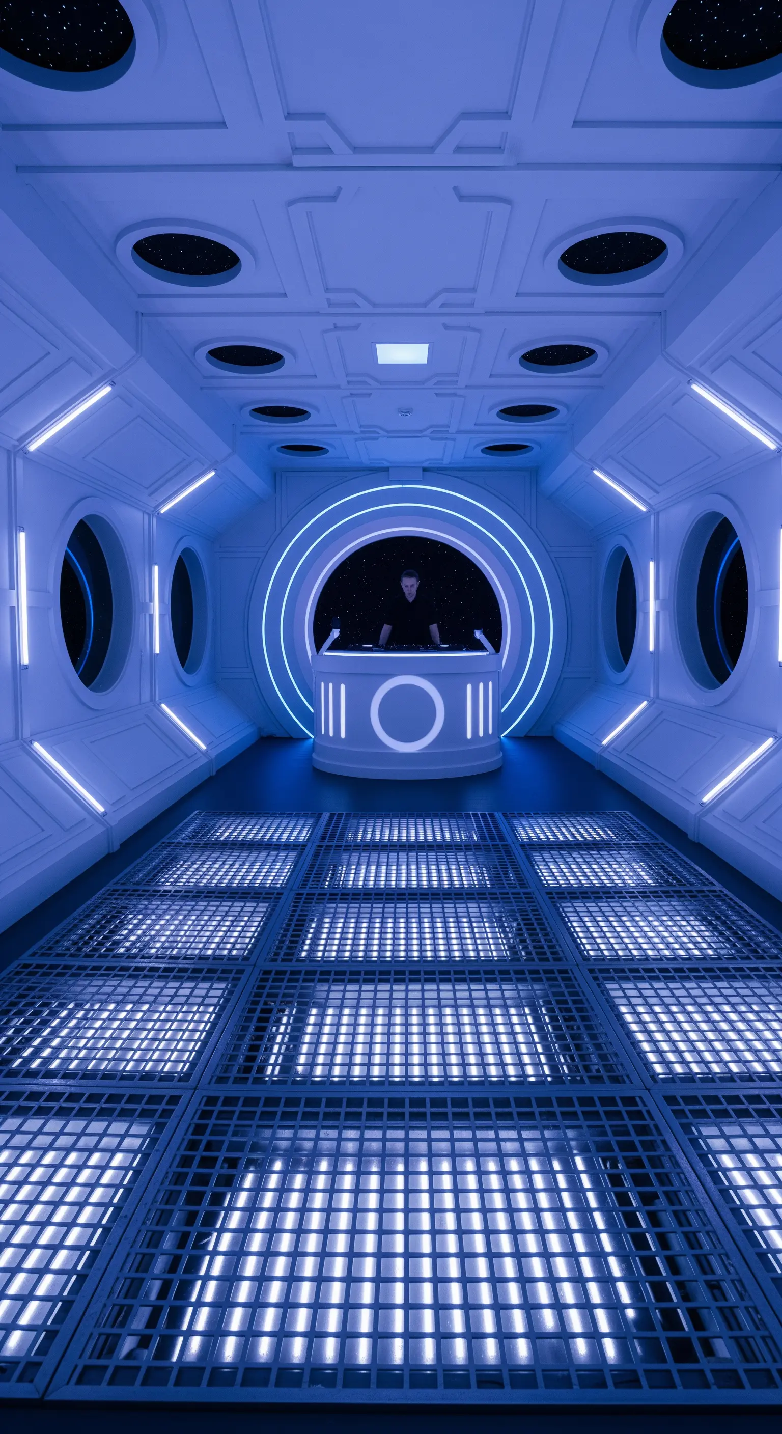 DJ booth all'interno di un corridoio di un'astronave con illuminazione a LED bianca.
