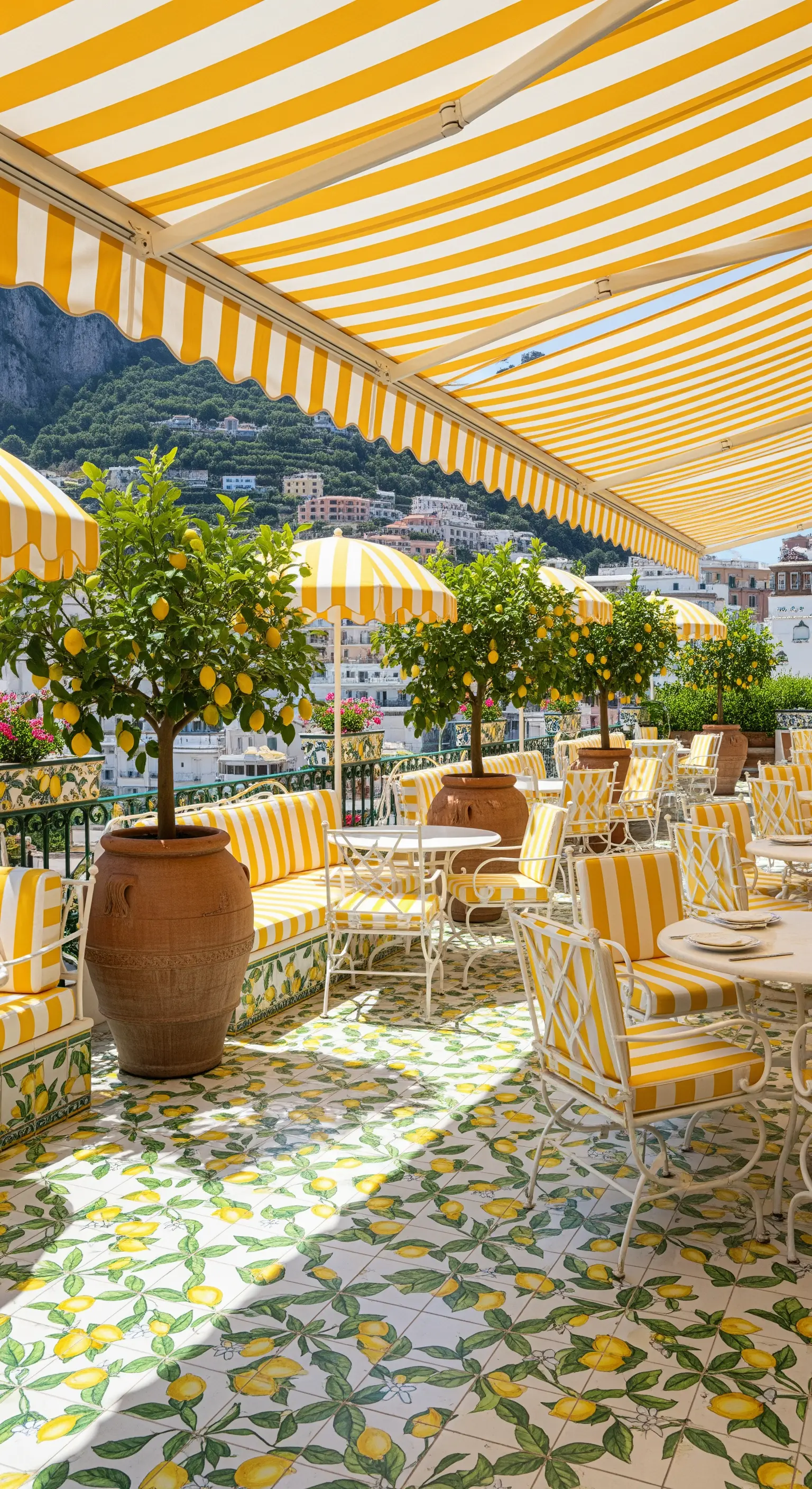 Terrazza con tende da sole, sedie e cuscini a righe gialle e bianche, e pavimento a tema limoni