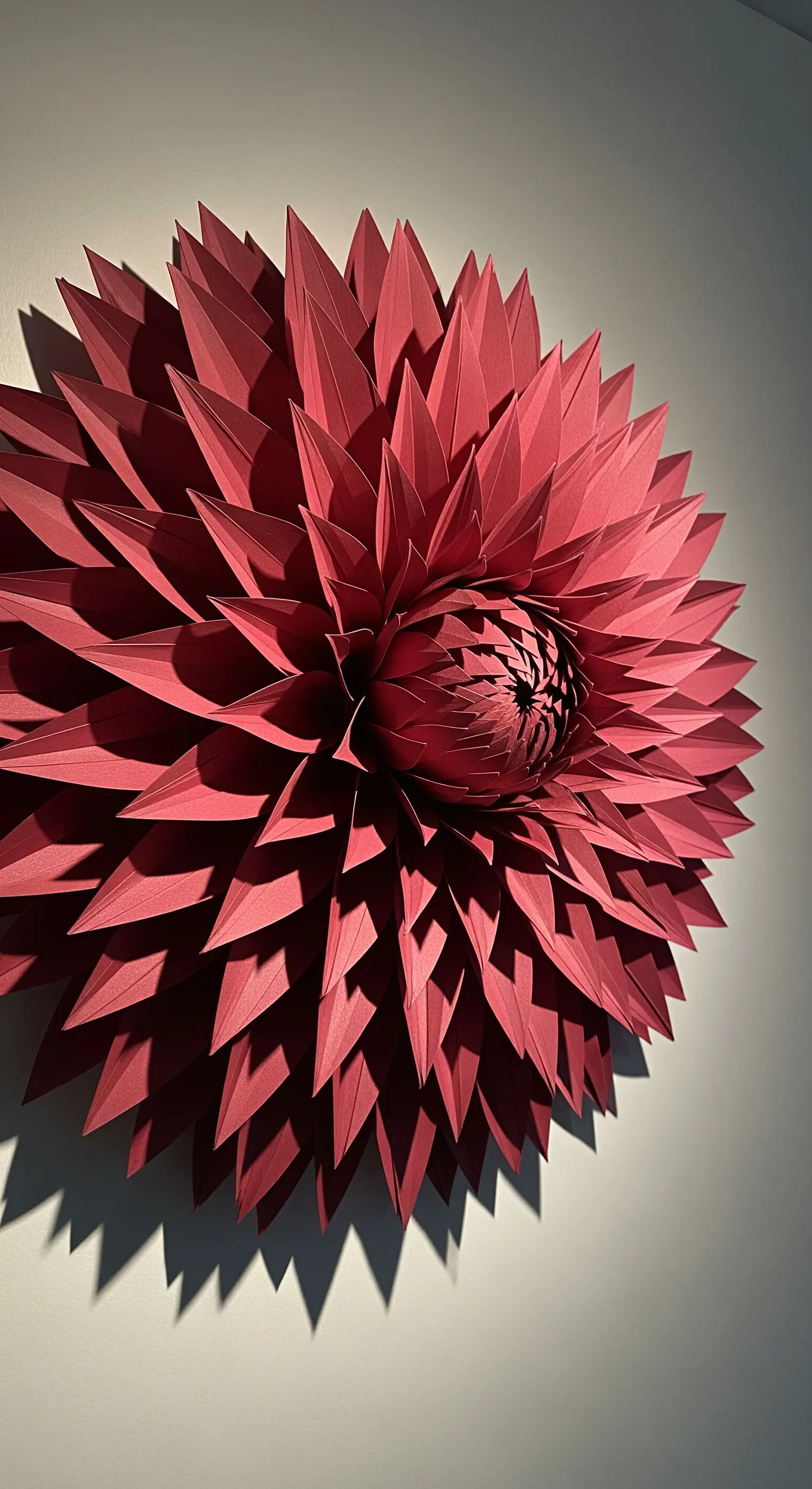 Un'enorme dahlia 3D di carta color magenta, con petali appuntiti che creano un effetto tridimensionale.