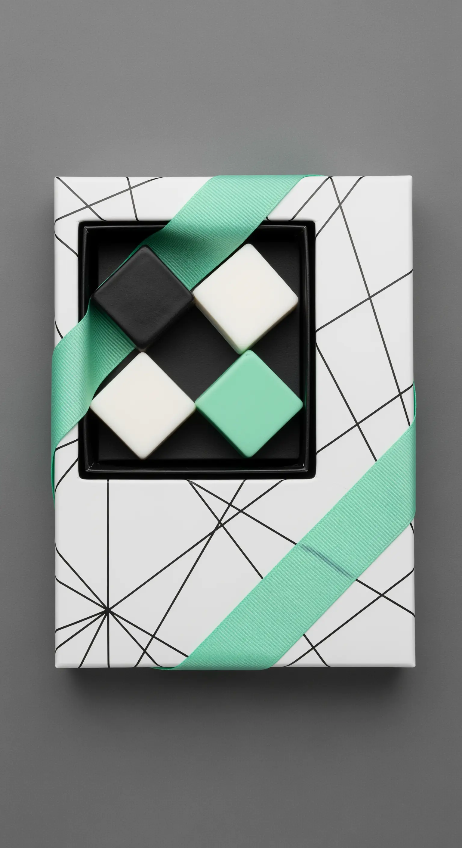 Scatola con motivo geometrico bianco e nero, con saponi e un nastro verde menta.