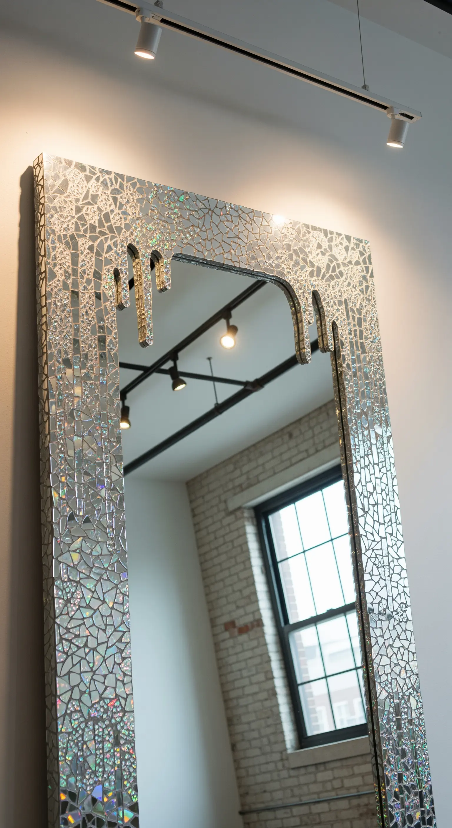 Grande specchio rettangolare con una cornice a mosaico che sembra sciogliersi dall'alto.