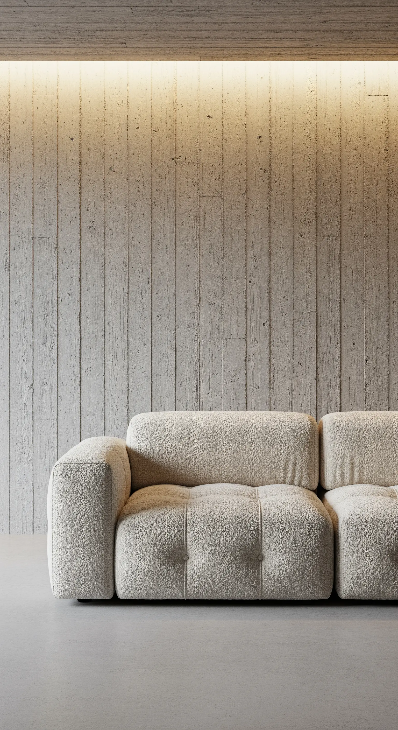 Dettaglio di un divano in tessuto bouclé bianco contro una parete in cemento grezzo