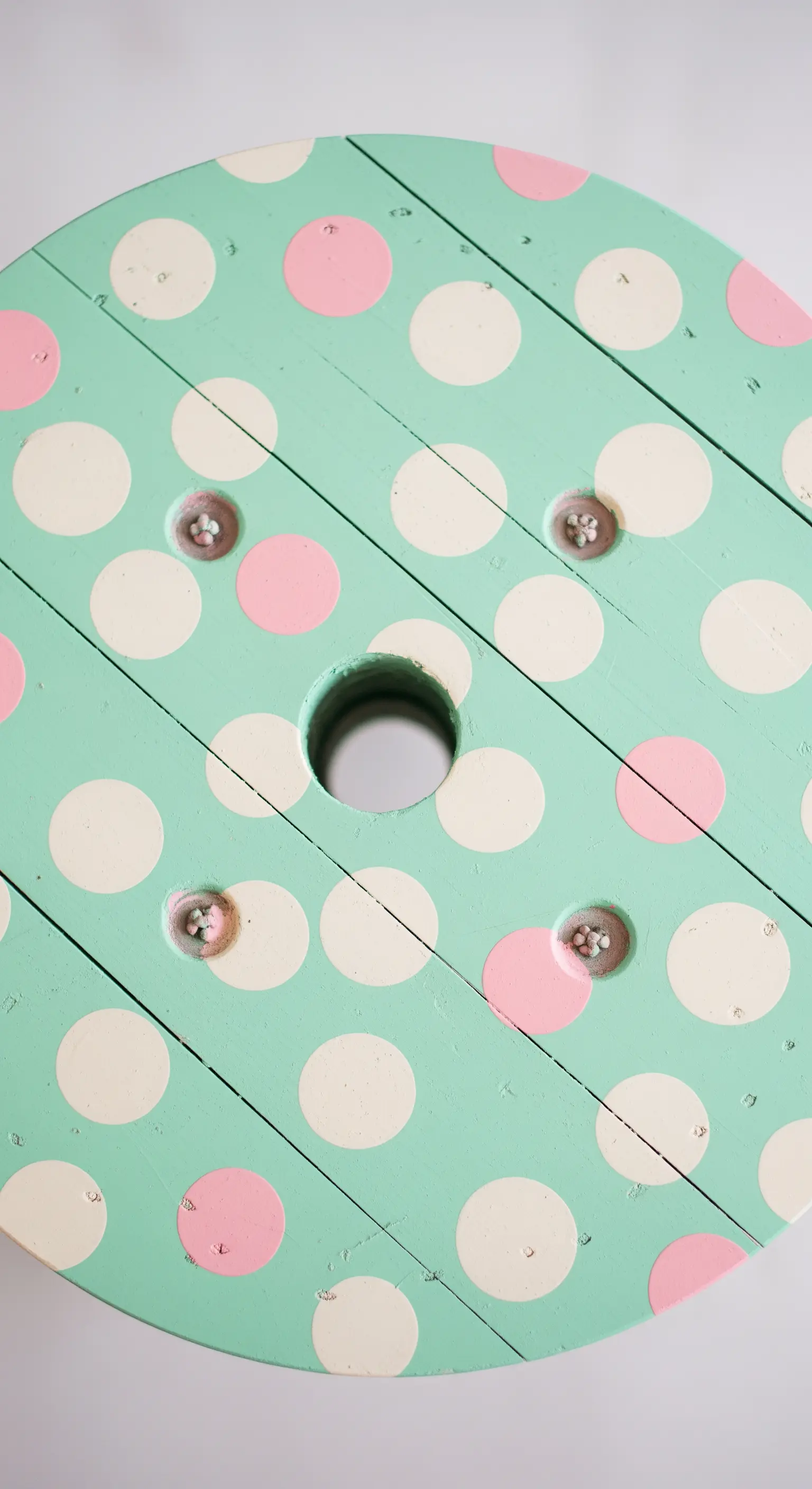 Dettaglio di un piano di un tavolo verde menta decorato con pois bianchi e rosa.