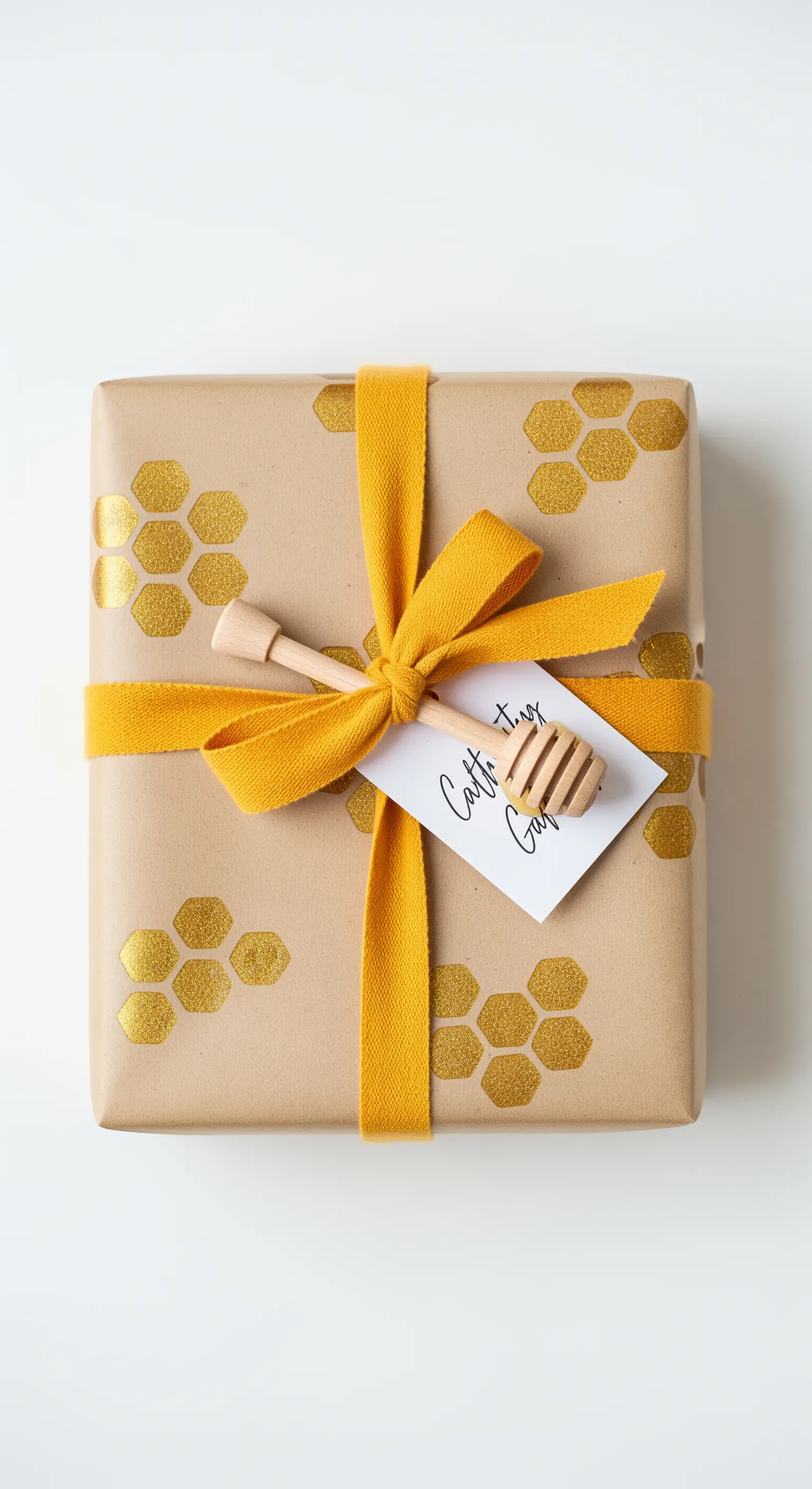 Pacco regalo in carta kraft con timbri dorati a nido d'ape e un piccolo spargimiele.
