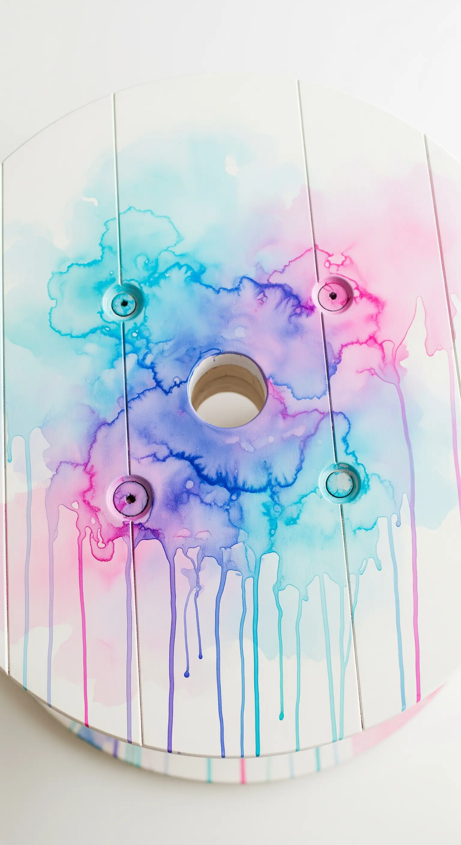 Piano di un tavolino bianco con macchie di colore rosa, blu e viola ad effetto acquerello.