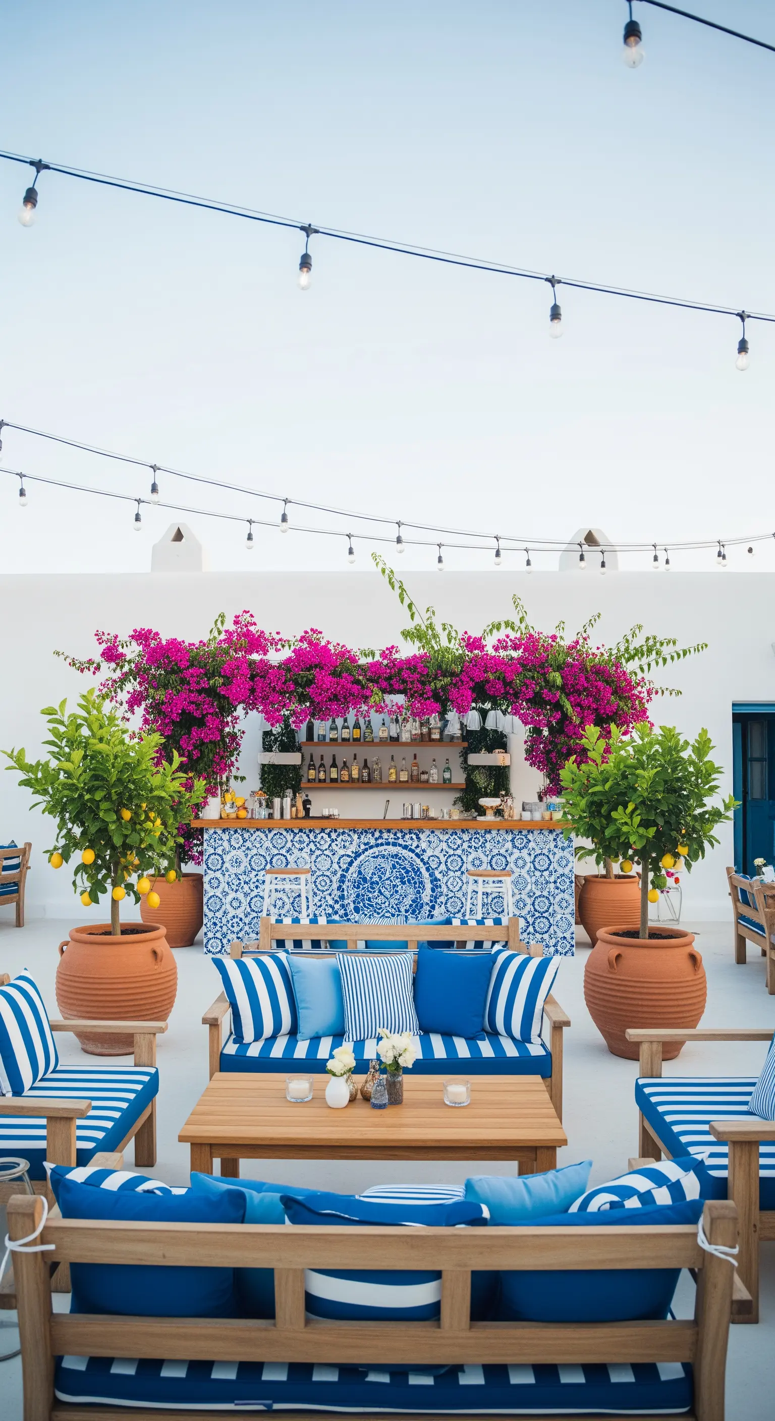 Terrazza in stile mediterraneo con divani a righe blu, bougainvillea e bar con maioliche.