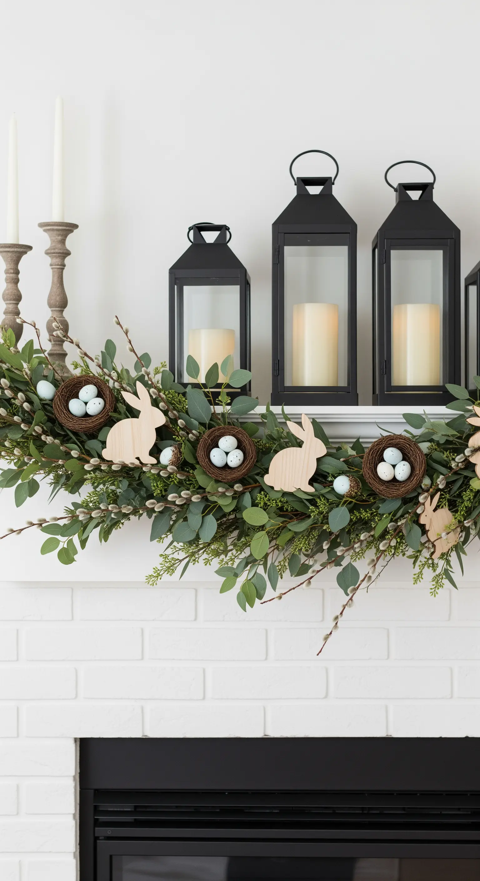 Decorazione per camino pasquale con lanterne nere, ghirlanda di eucalipto e nidi.