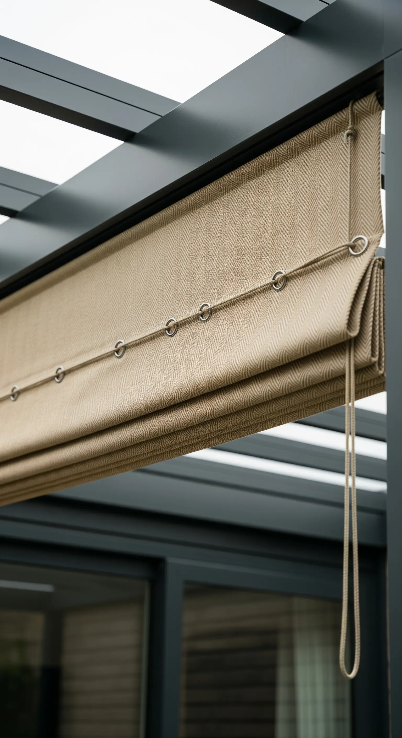 Tenda a pacchetto beige con meccanismo a corde e anelli, installata sotto un pergolato.