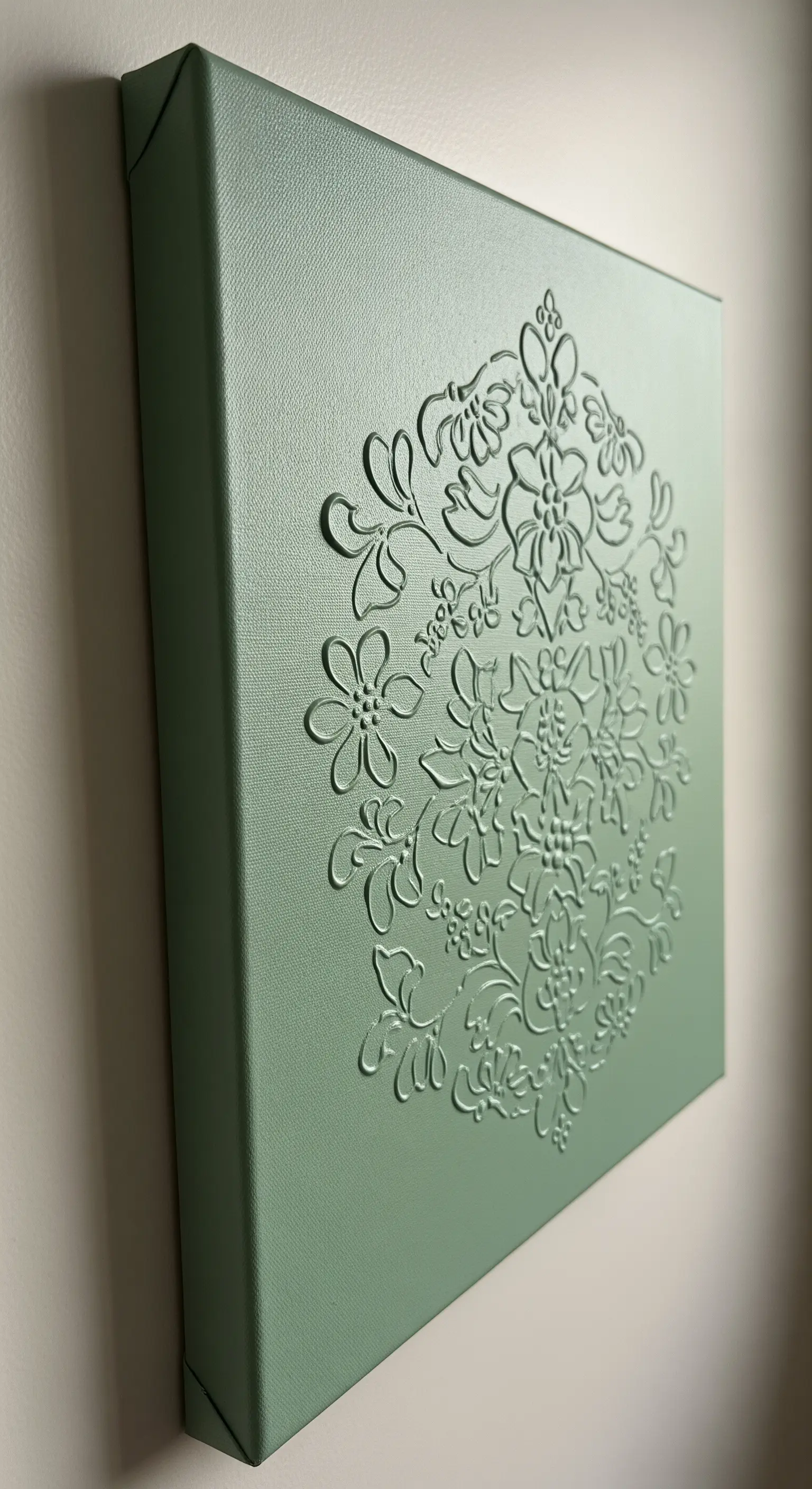 Quadro monocromatico verde salvia con un disegno floreale a rilievo creato con la colla a caldo.