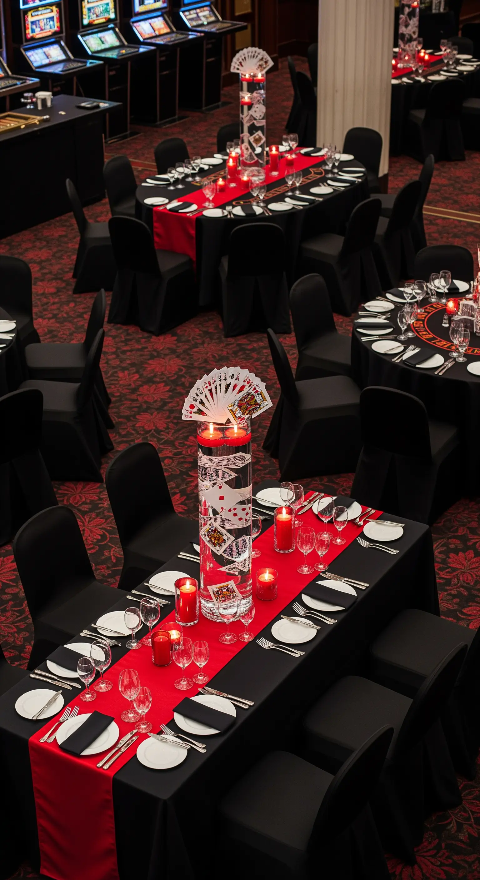 Tavoli da pranzo neri con runner rossi e centrotavola a tema carte da gioco.