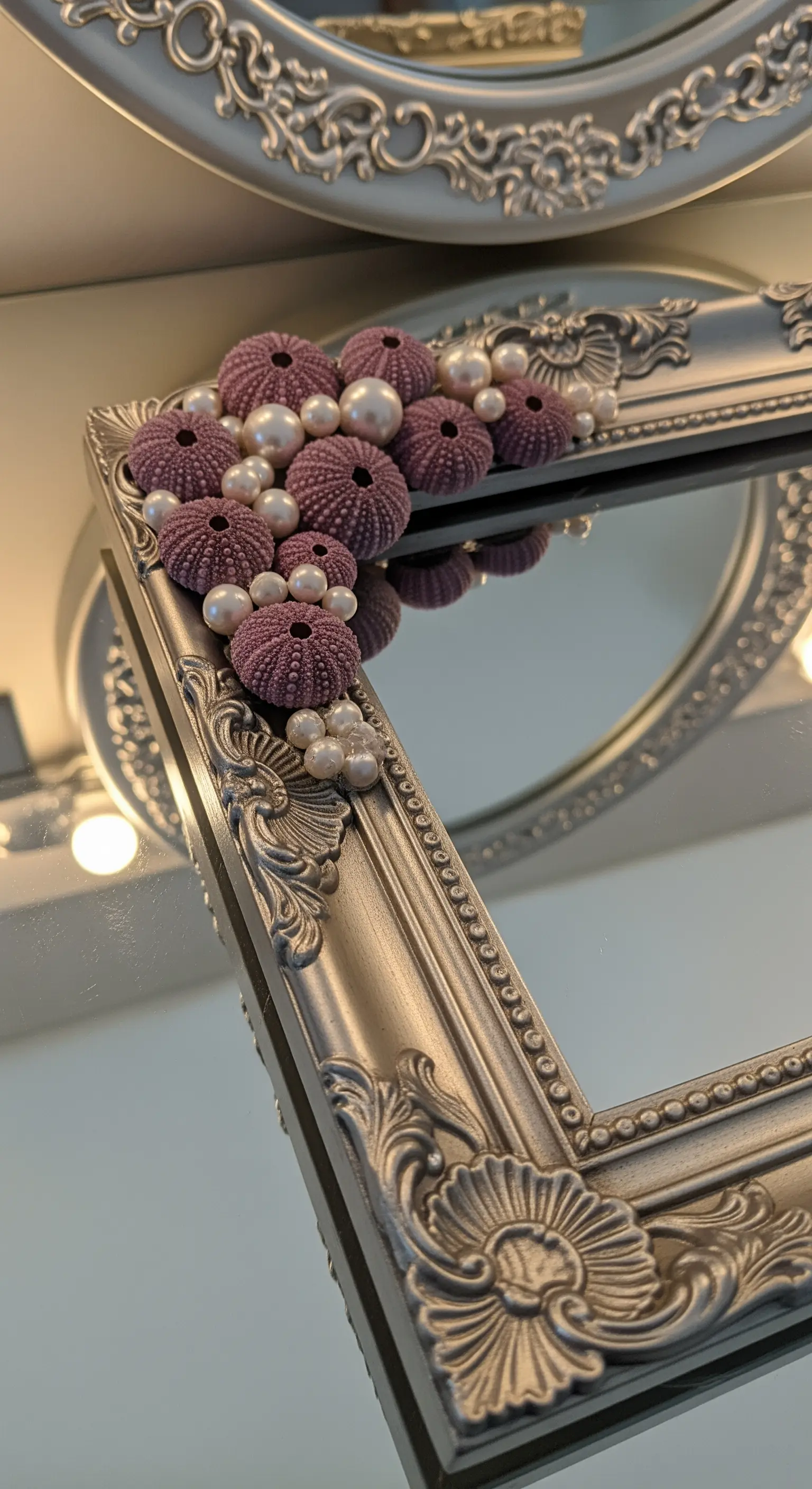 Dettaglio di una cornice argentata barocca con un'applicazione di ricci di mare viola e perle.