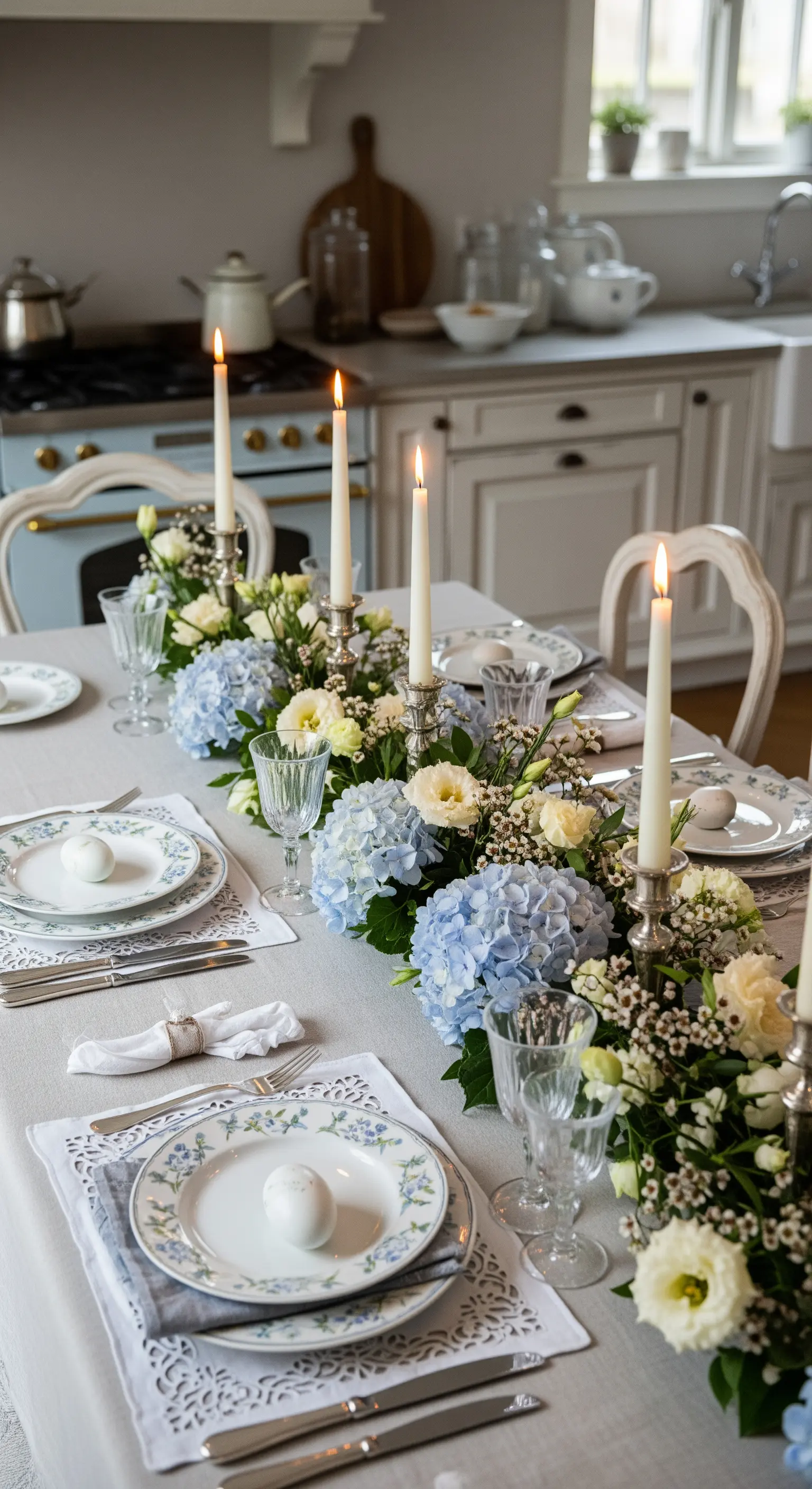 Tavola pasquale con runner di ortensie blu, candele bianche e piatti con motivi floreali.