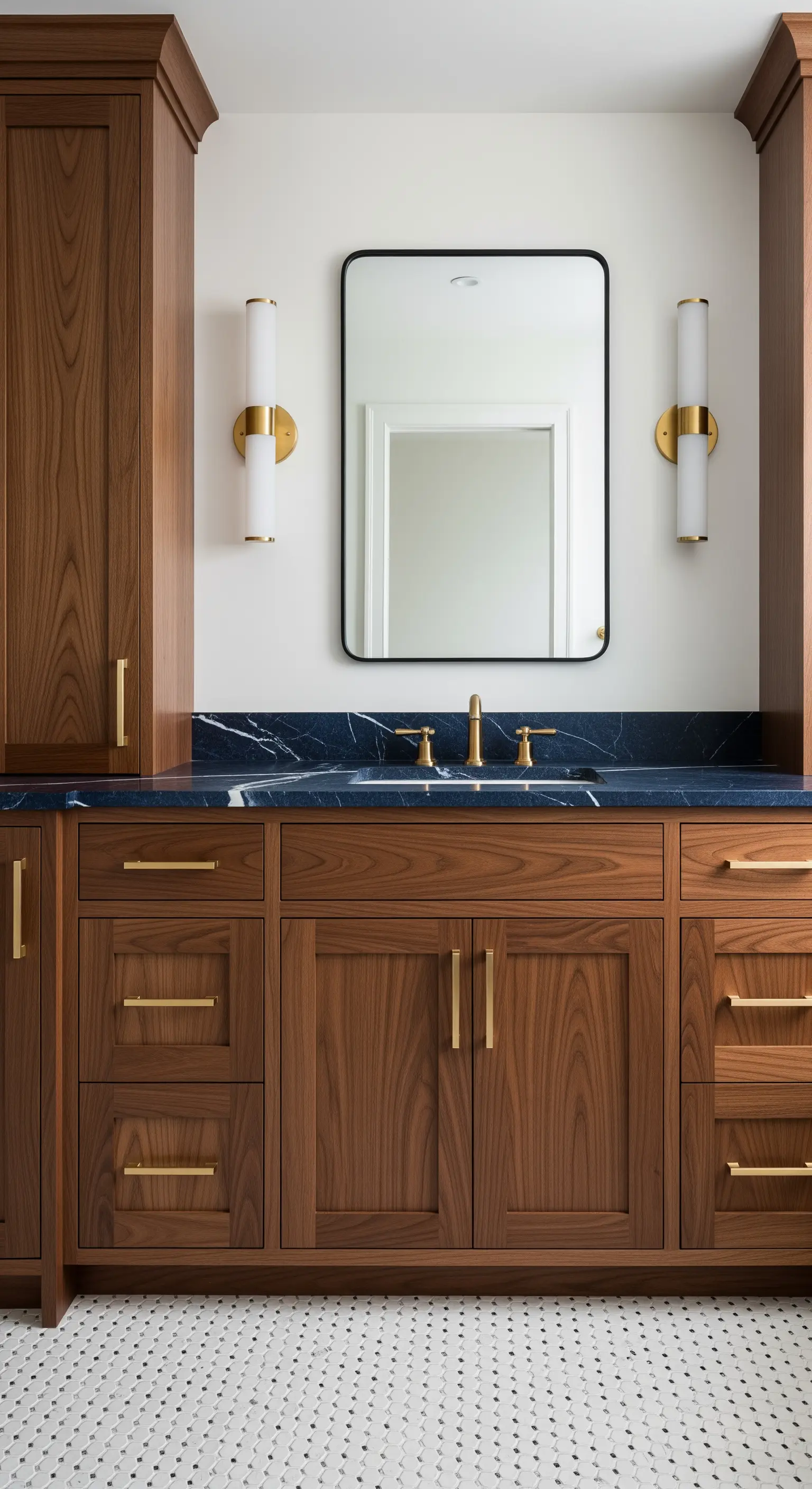 Mobile bagno in legno scuro con top in marmo blu, specchio con cornice nera e applique dorate.