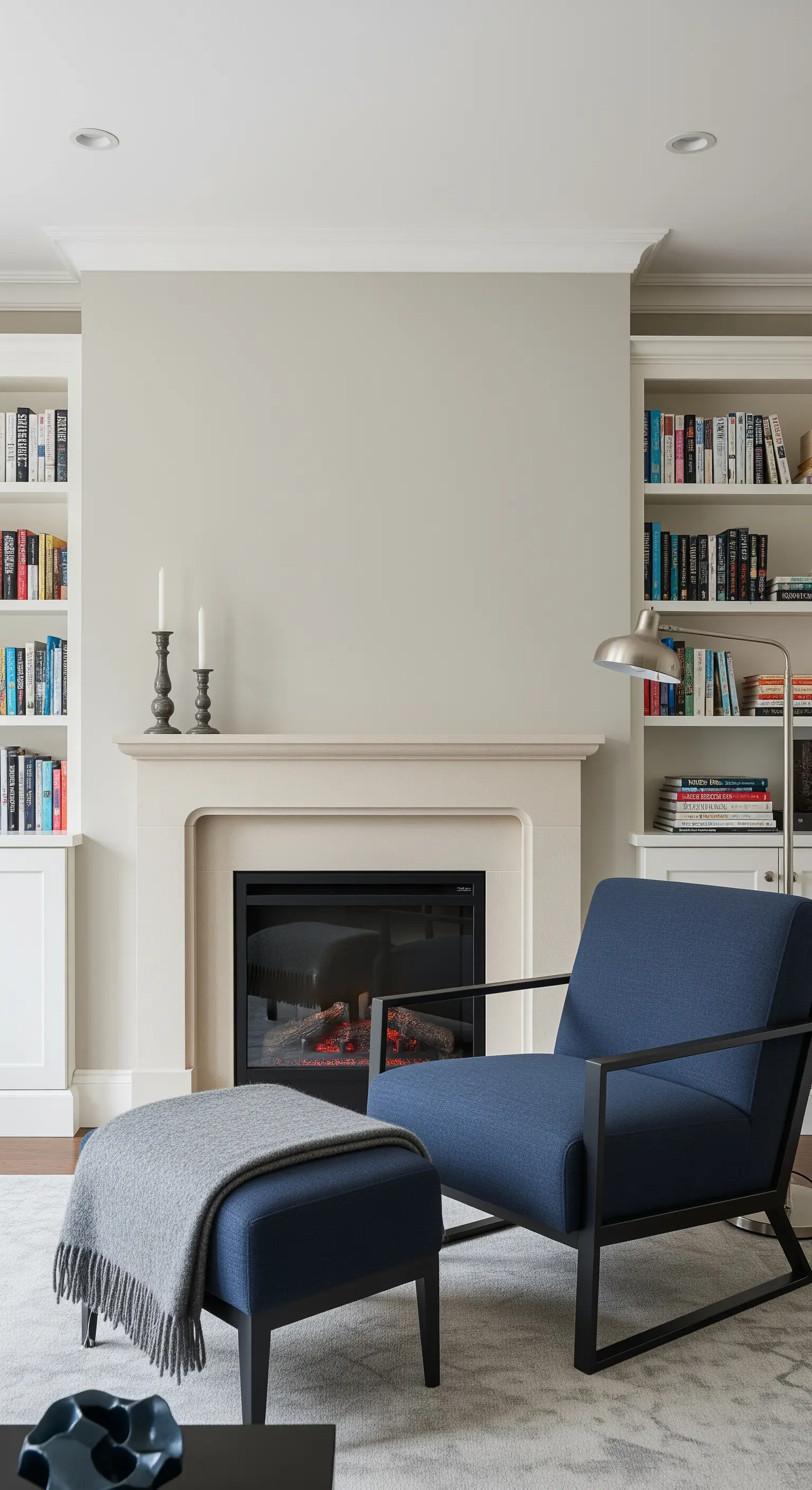 Angolo lettura contemporaneo con camino in pietra, librerie a incasso e poltrona blu.