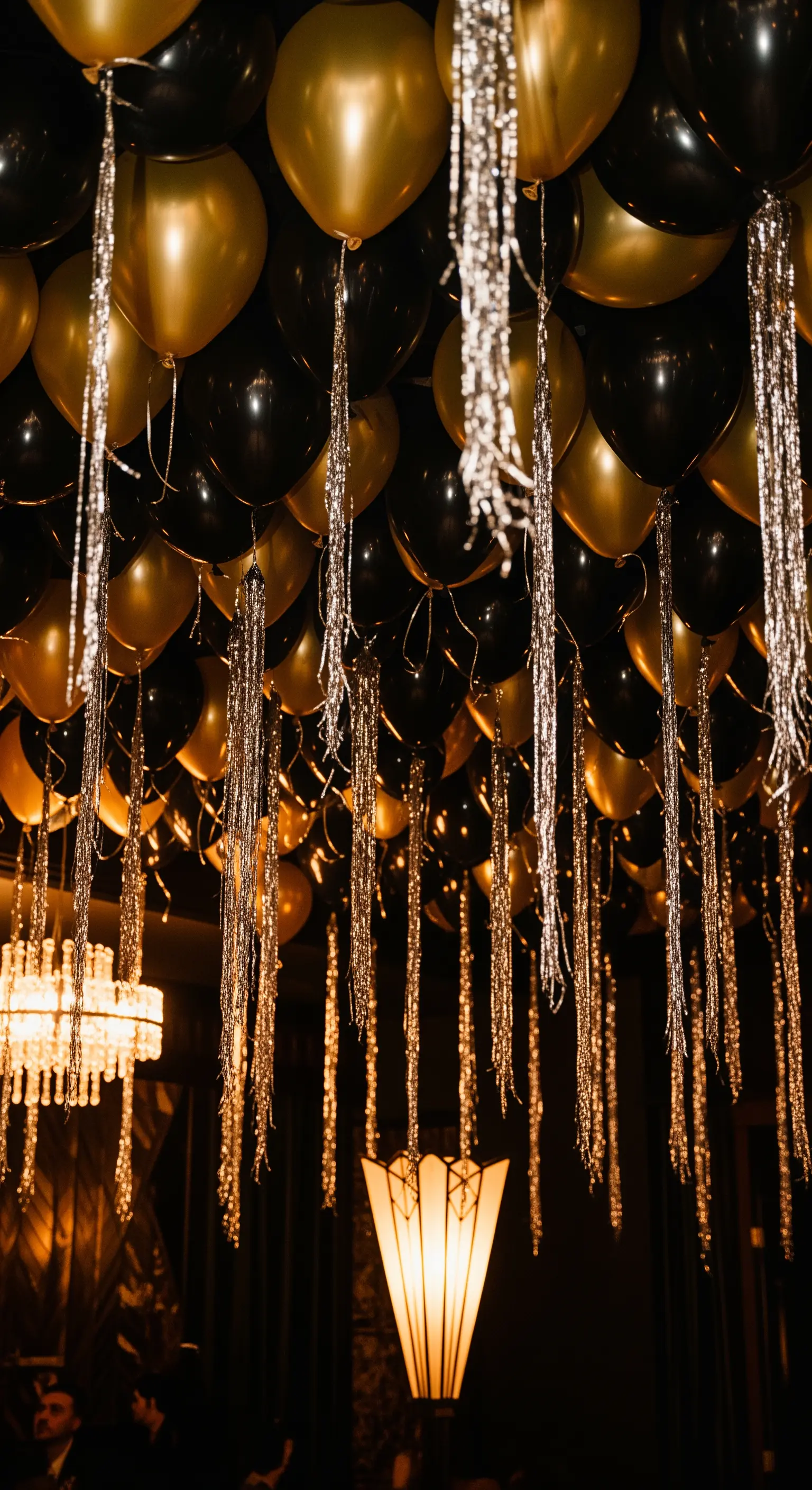 Un soffitto scuro coperto da palloncini neri e oro con lunghe frange metalliche.