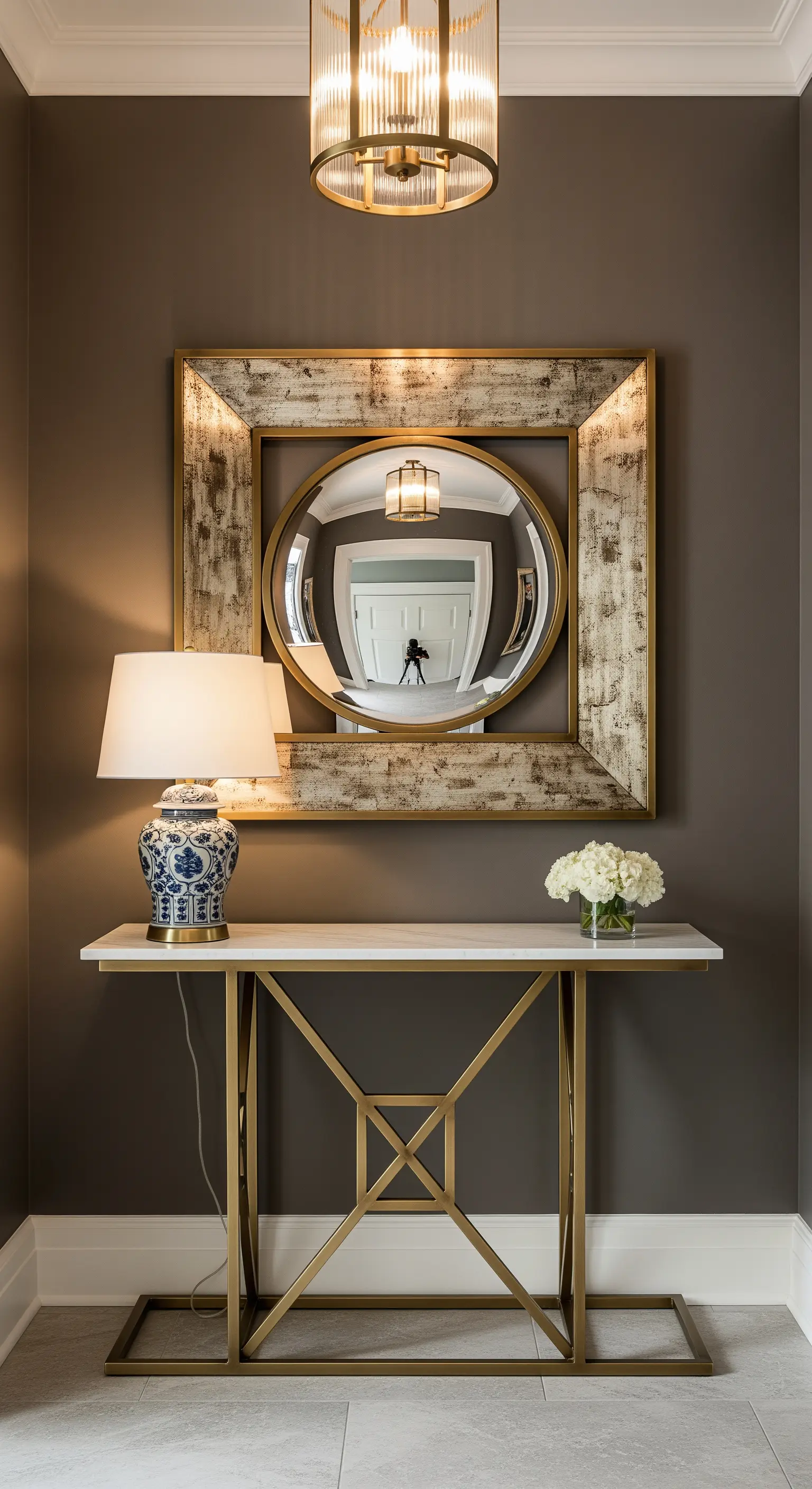 Ingresso con parete grigio-marrone e specchio tondo inserito in una cornice quadrata.