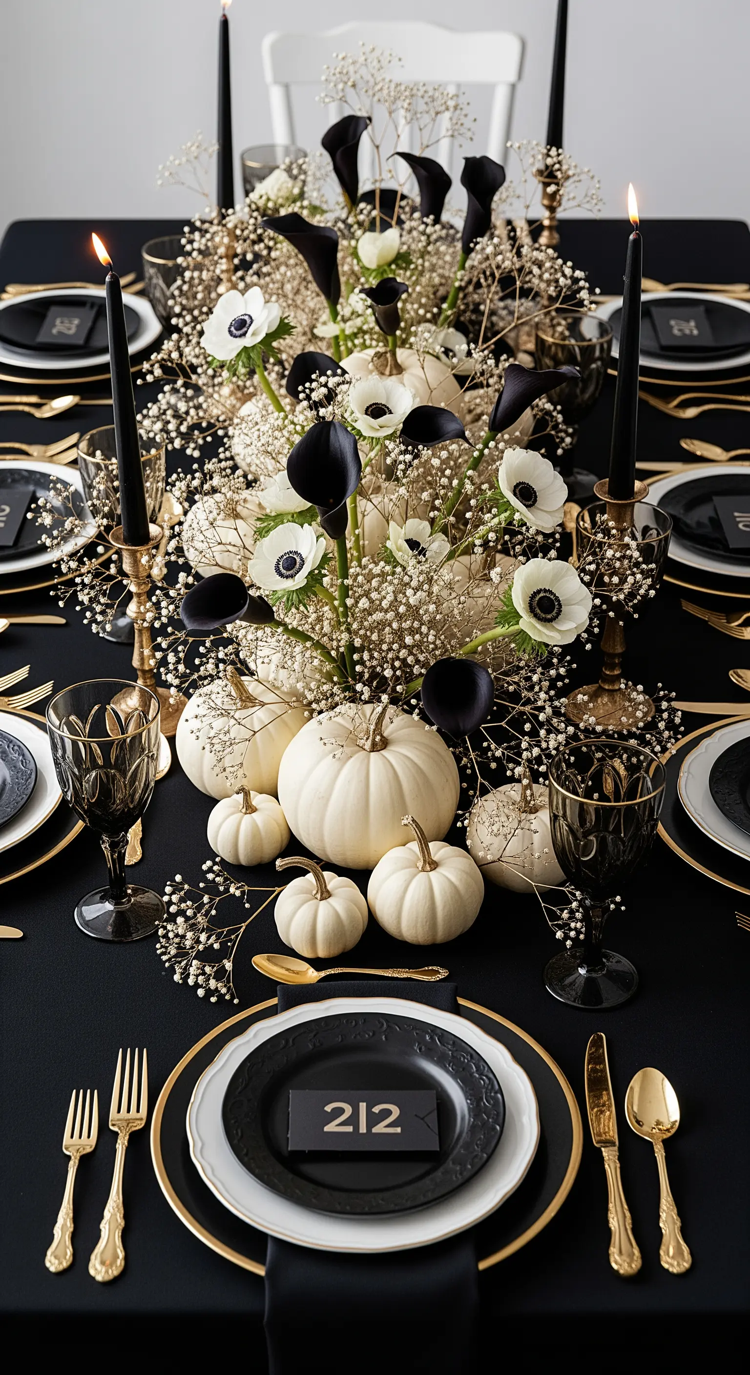 Centrotavola floreale con calle nere, anemoni bianchi e zucche su una tavola nera.