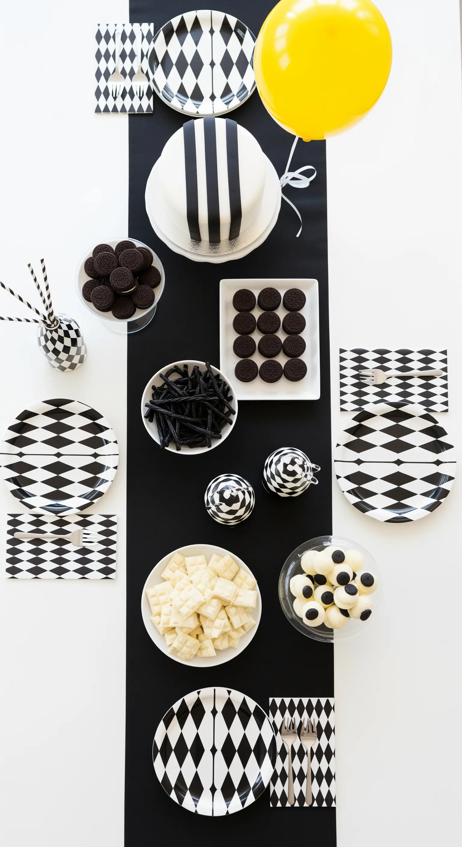 Tavola minimalista in bianco e nero con dolci coordinati e un palloncino giallo a contrasto.