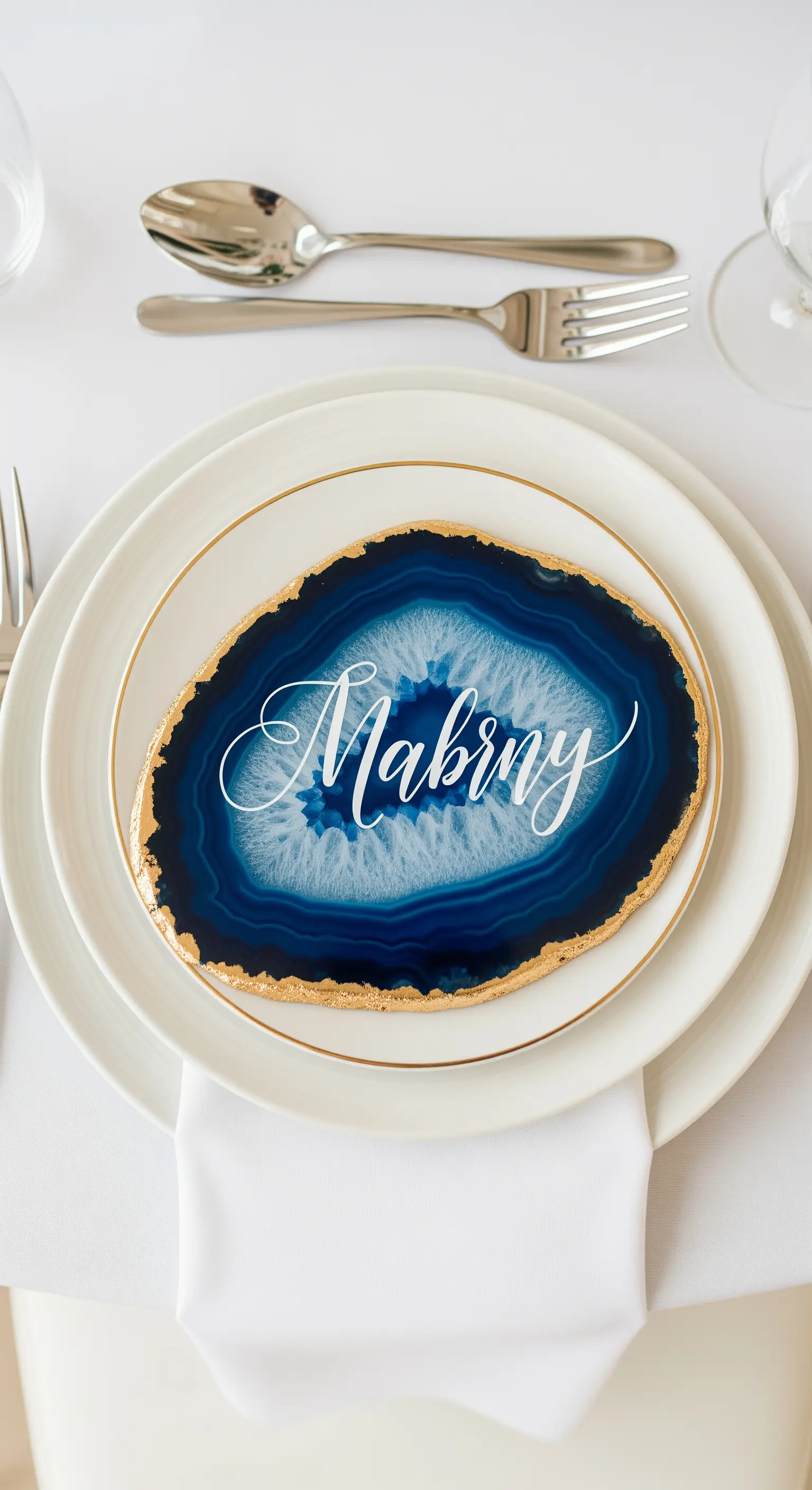 Segnaposto in agata blu con bordi dorati e nome scritto in calligrafia bianca.