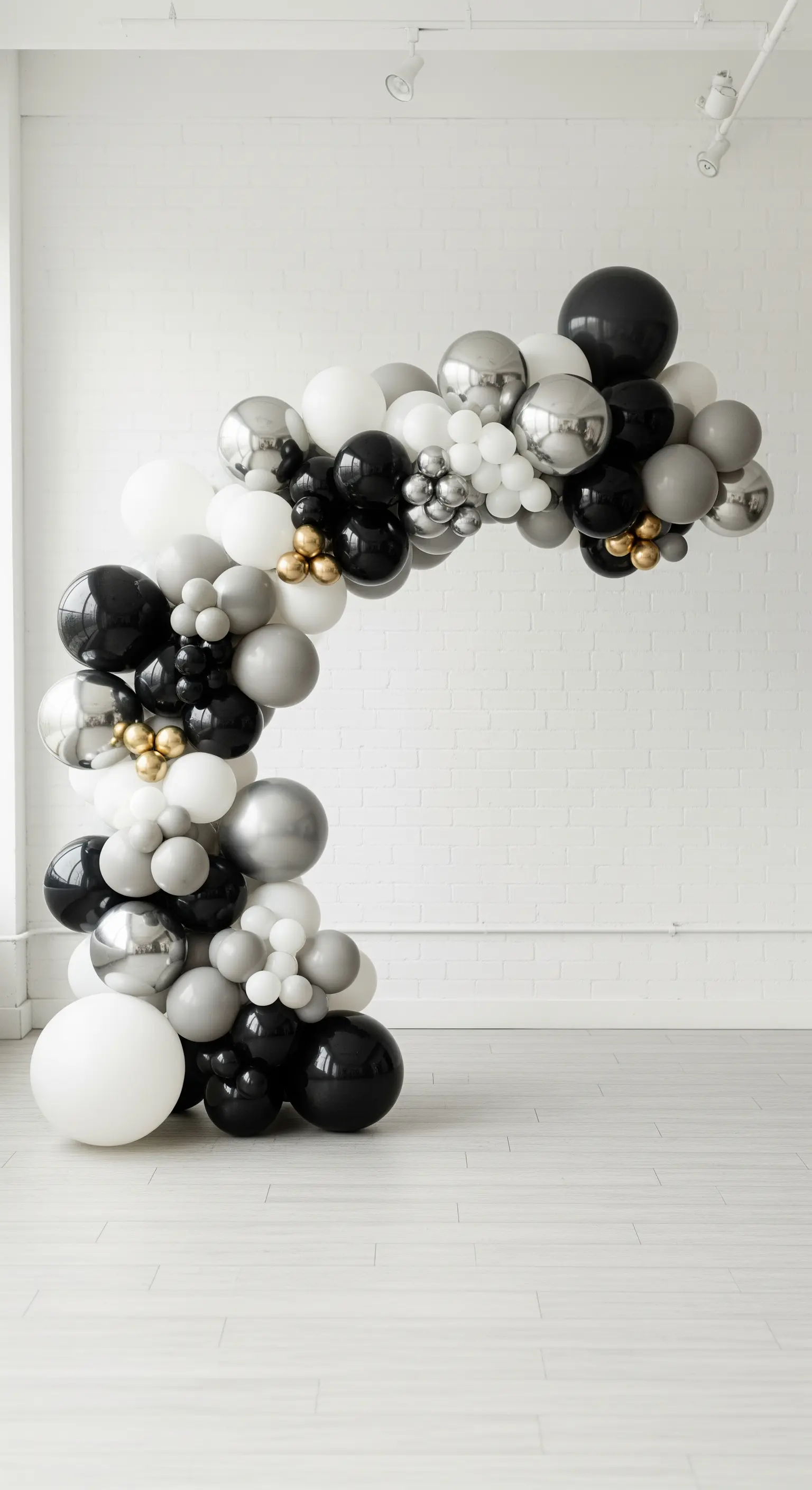 Arco di palloncini in bianco, nero e argento con piccoli dettagli dorati.