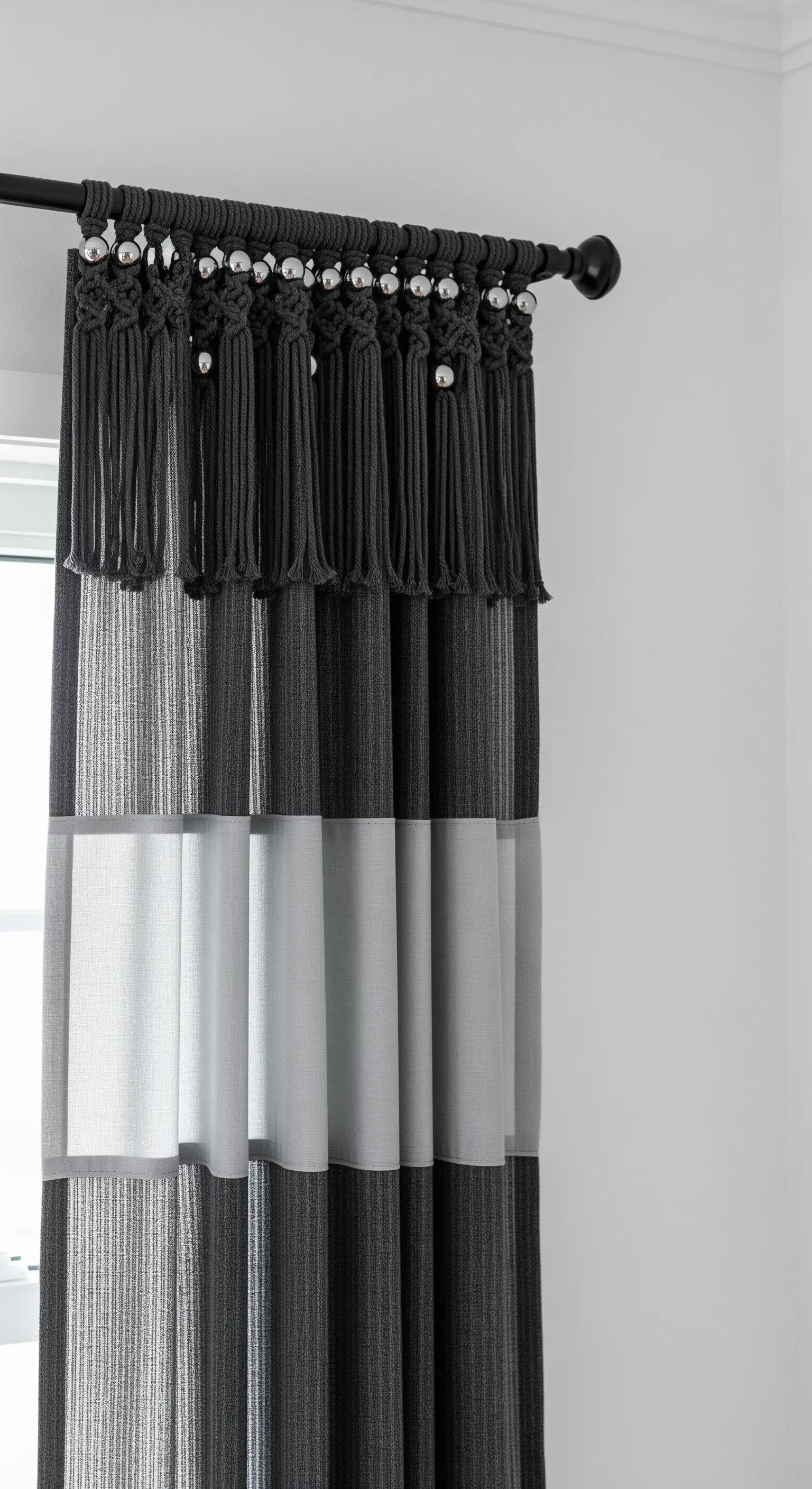 Tenda a righe grigie con mantovana in macramè scuro e perle argentate decorative.