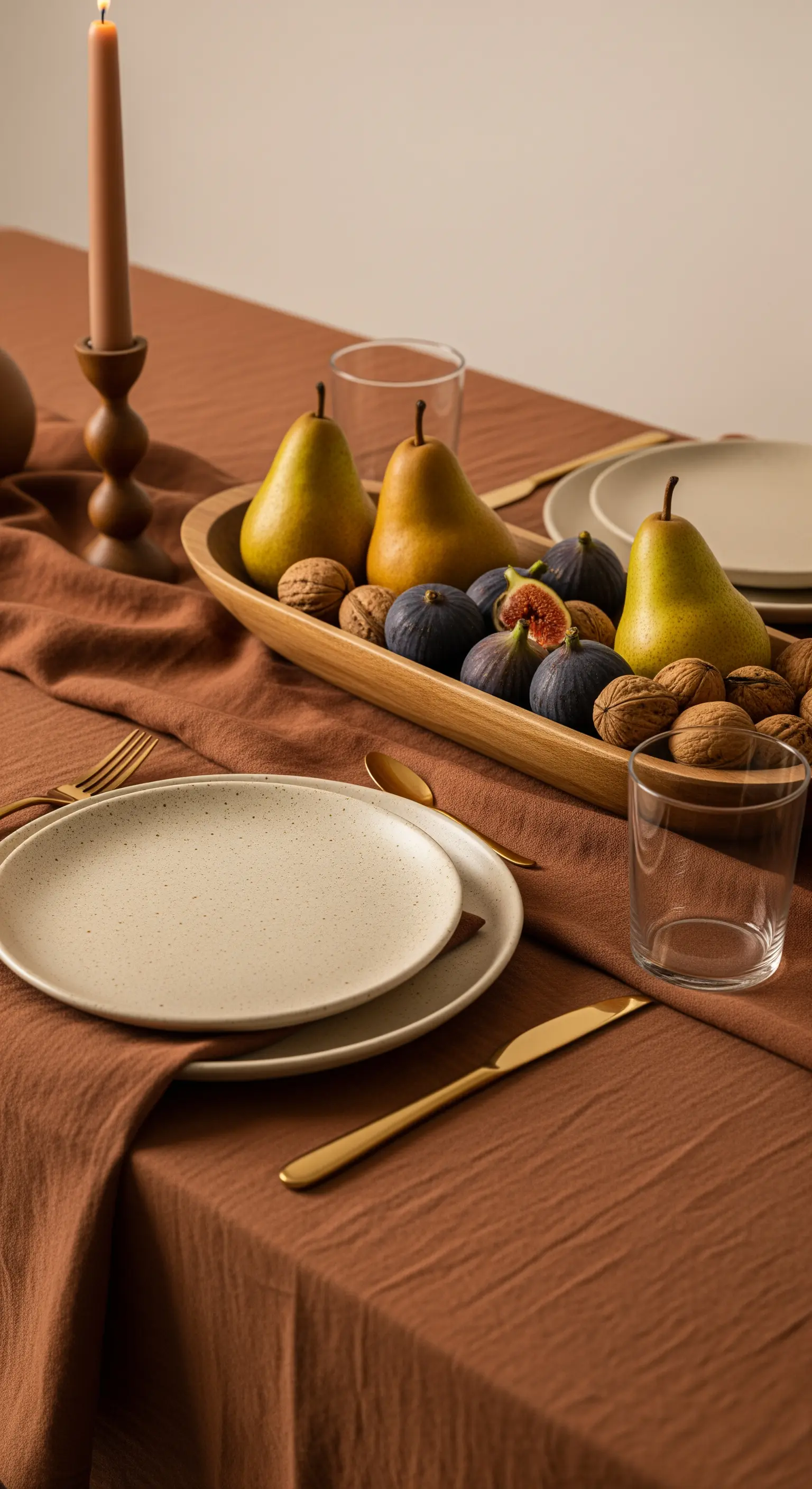 Centrotavola con pere e fichi in una ciotola di legno su tovaglia marrone.