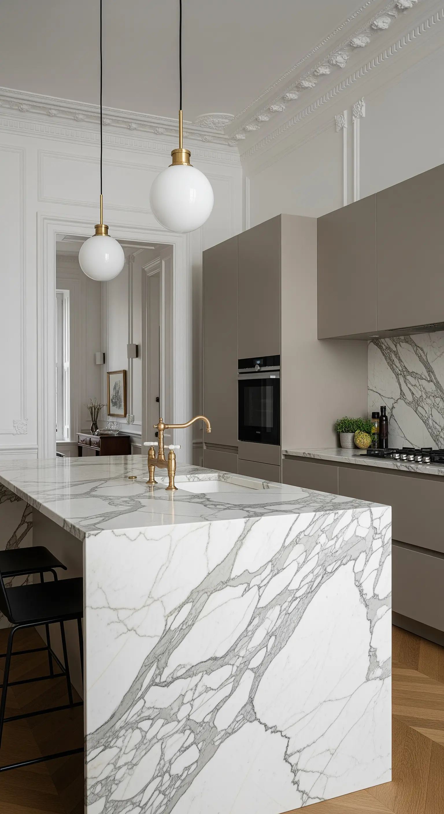 Isola in marmo con venature grigie in un appartamento elegante con boiserie e pavimento a spina di pesce.