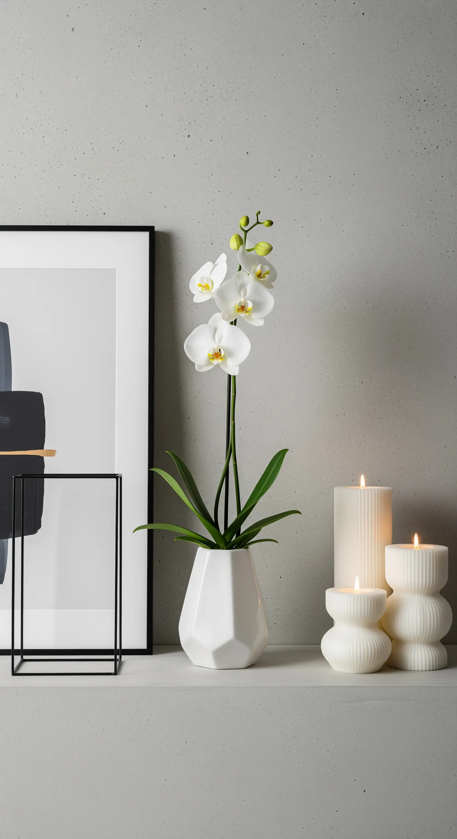 Orchidea bianca in un vaso geometrico, affiancata da candele scultoree e arte astratta.