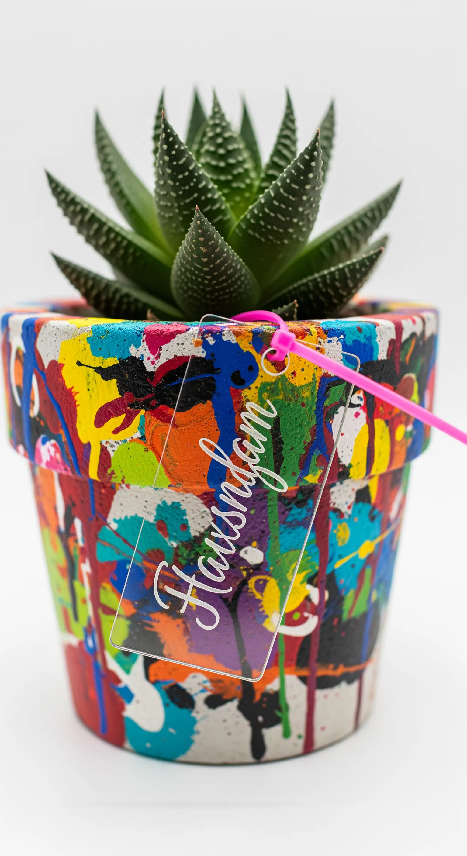 Vaso di terracotta con schizzi di vernice colorata in stile action painting e un'etichetta in acrilico.