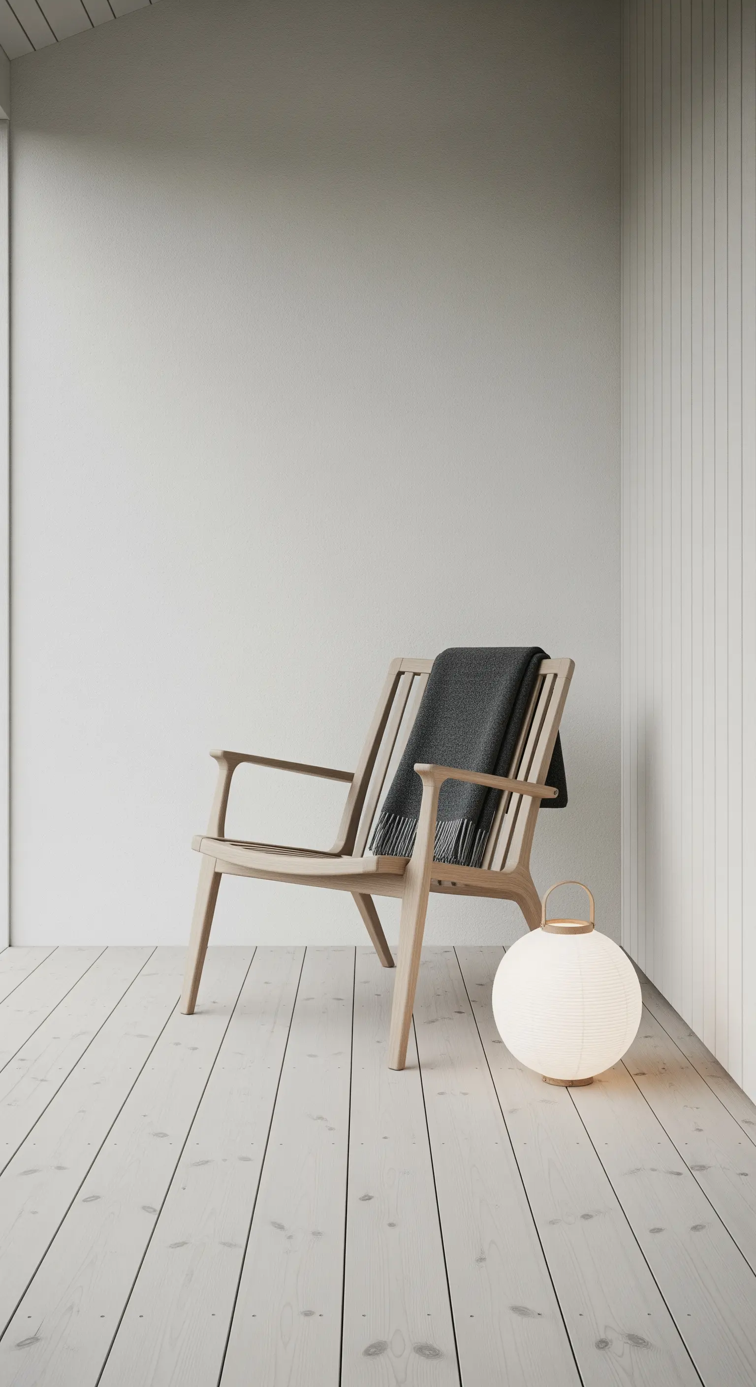 Angolo minimalista con poltrona in legno chiaro, plaid scuro e lampada sferica a terra