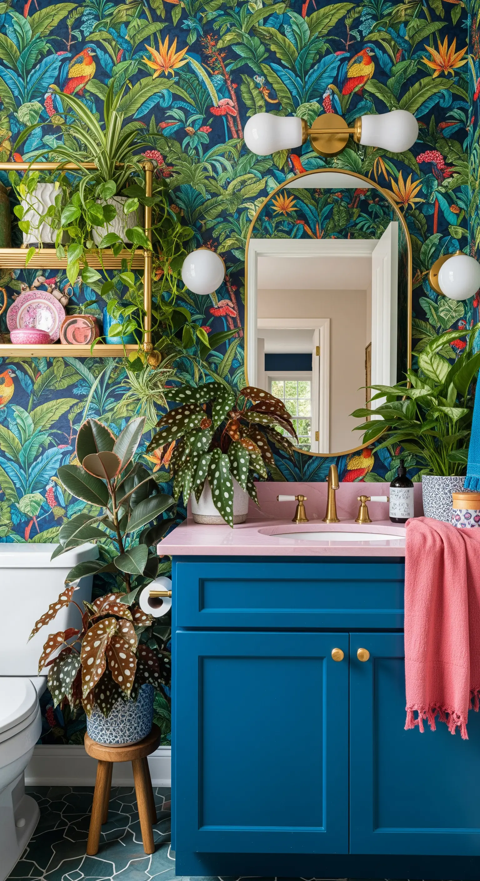 Bagno con audace carta da parati tropicale, mobile blu e lavabo rosa.