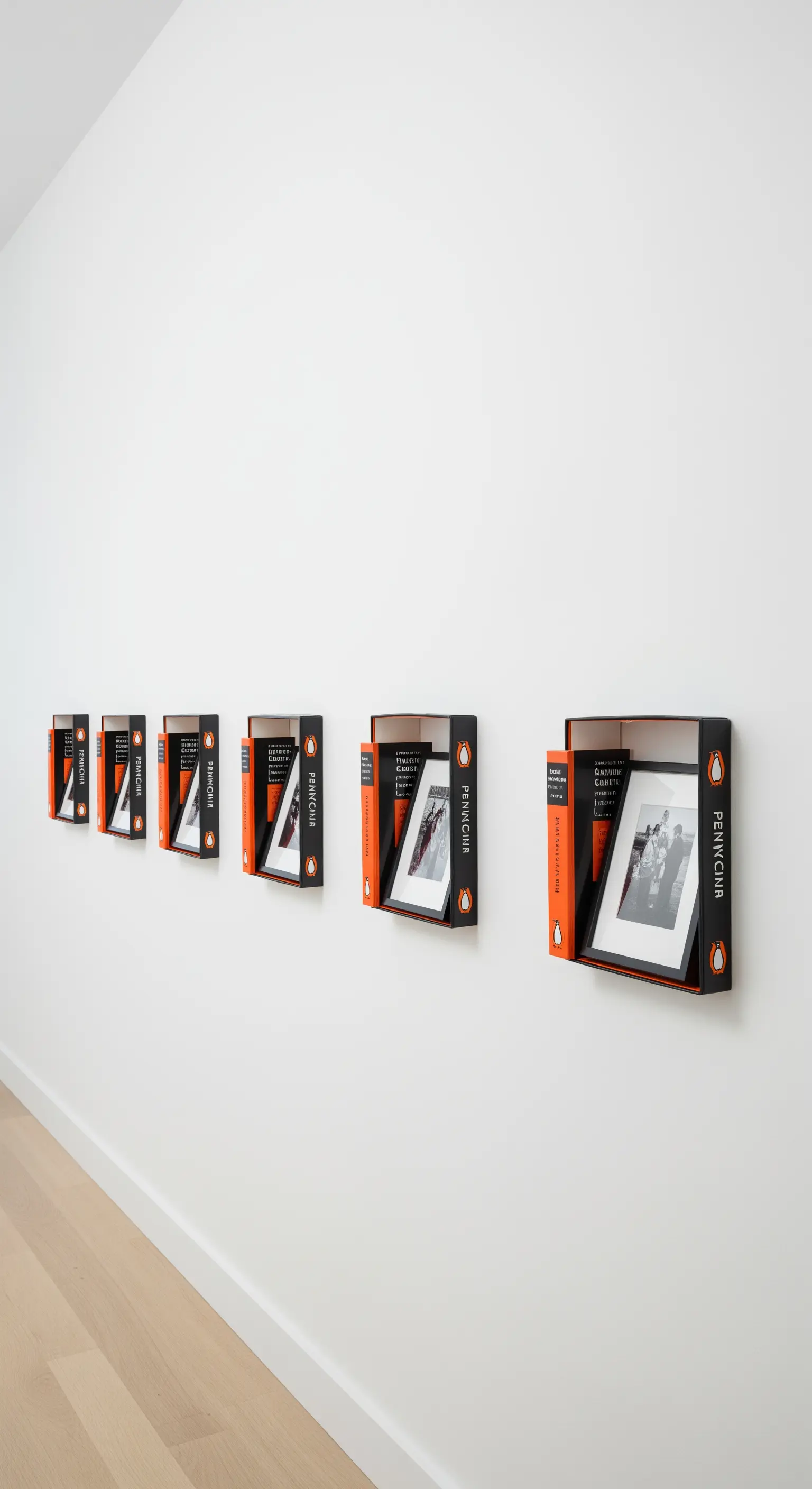 Serie di libri tascabili appesi in fila su una parete bianca, usati come cornici per foto.
