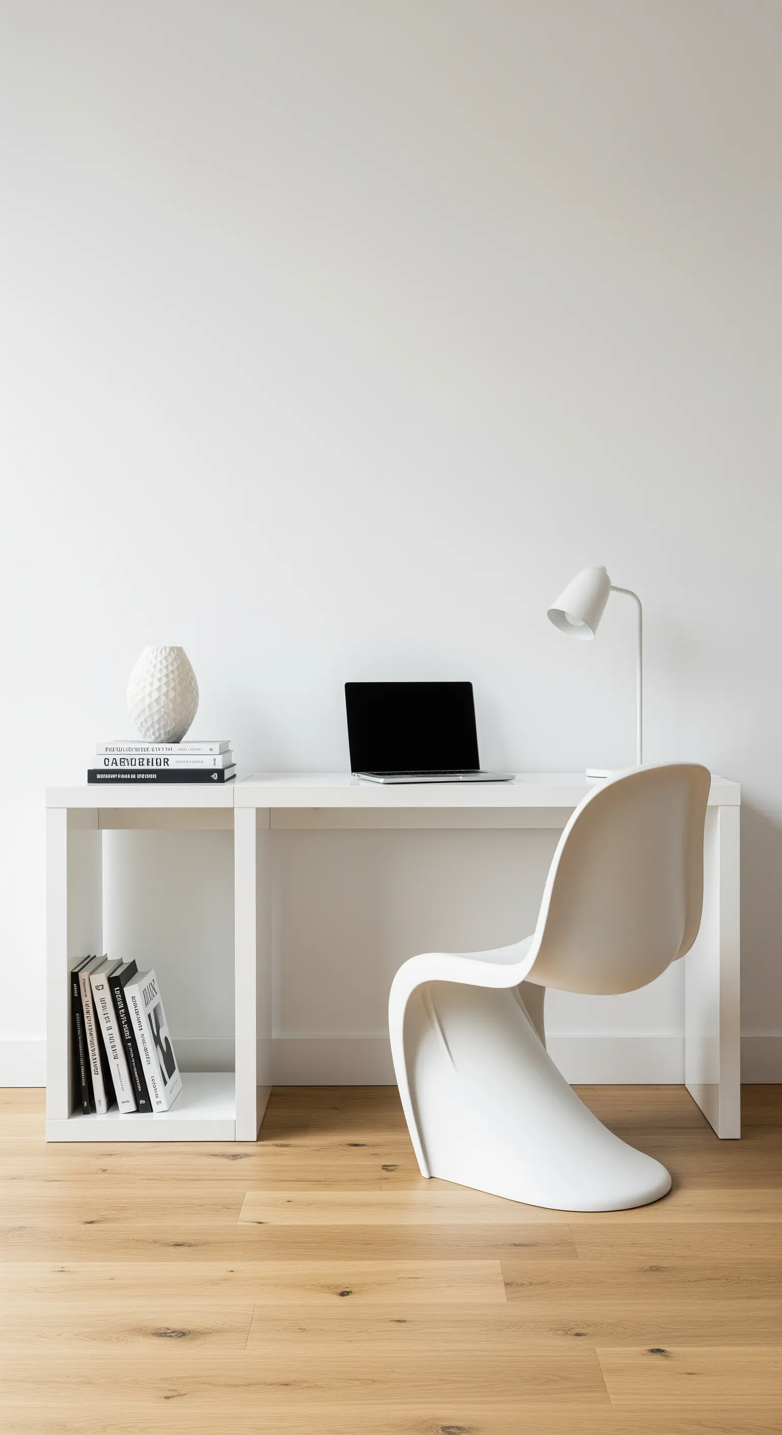 Scrivania-console bianca con una sedia Panton bianca e pochi libri d'arredo.
