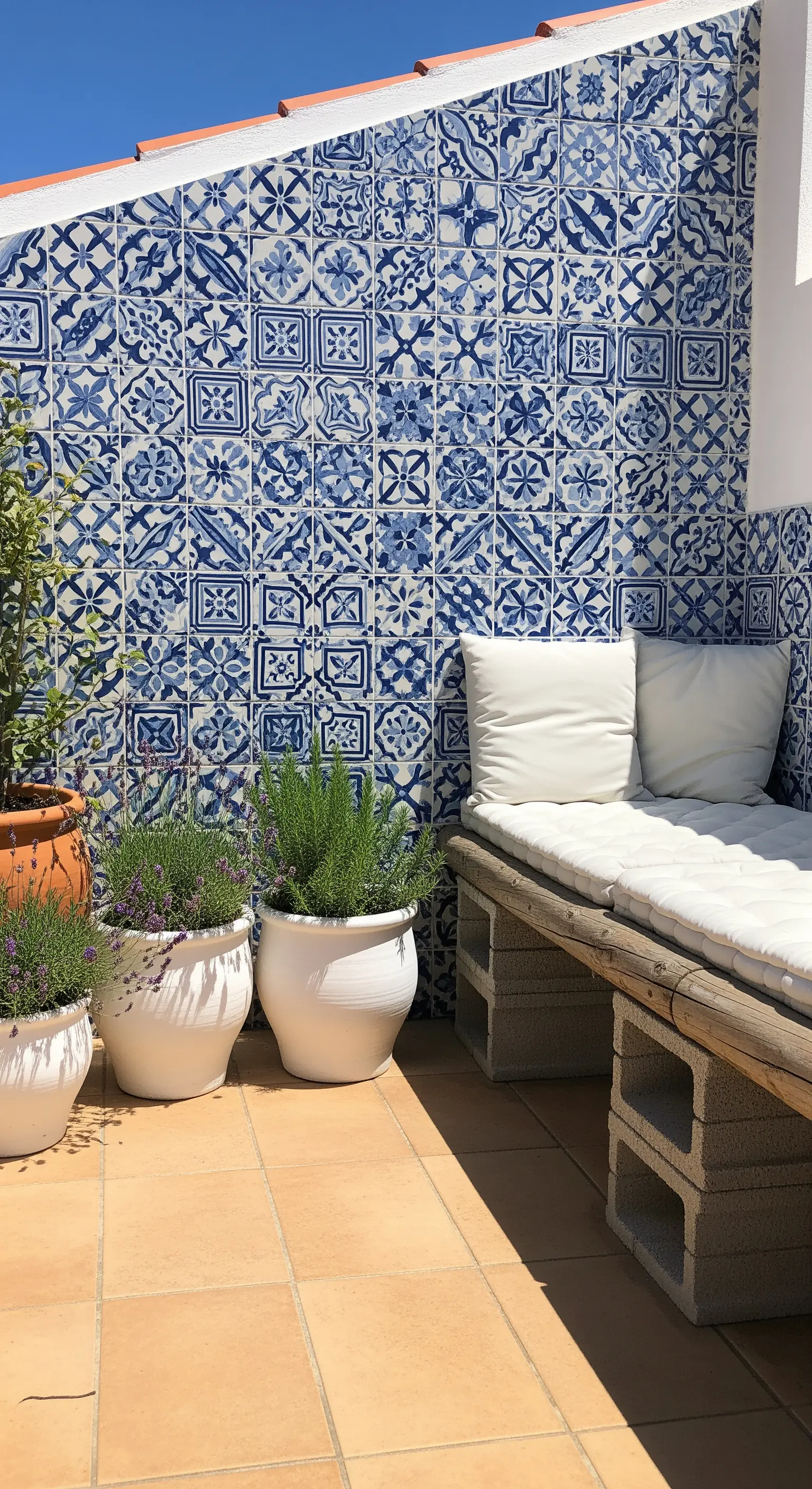 Terrazza con parete di piastrelle azulejos, panca in blocchi di cemento e vasi di lavanda.