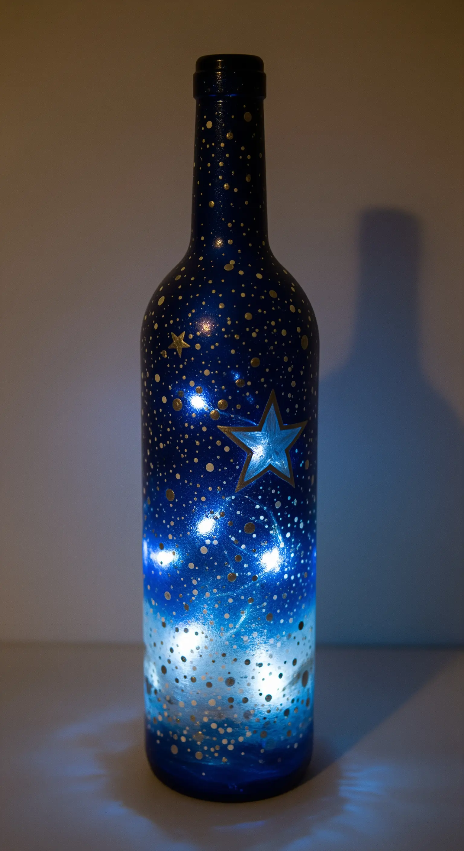 Bottiglia dipinta a mano con un cielo notturno sfumato, stelle dorate e lucine blu.