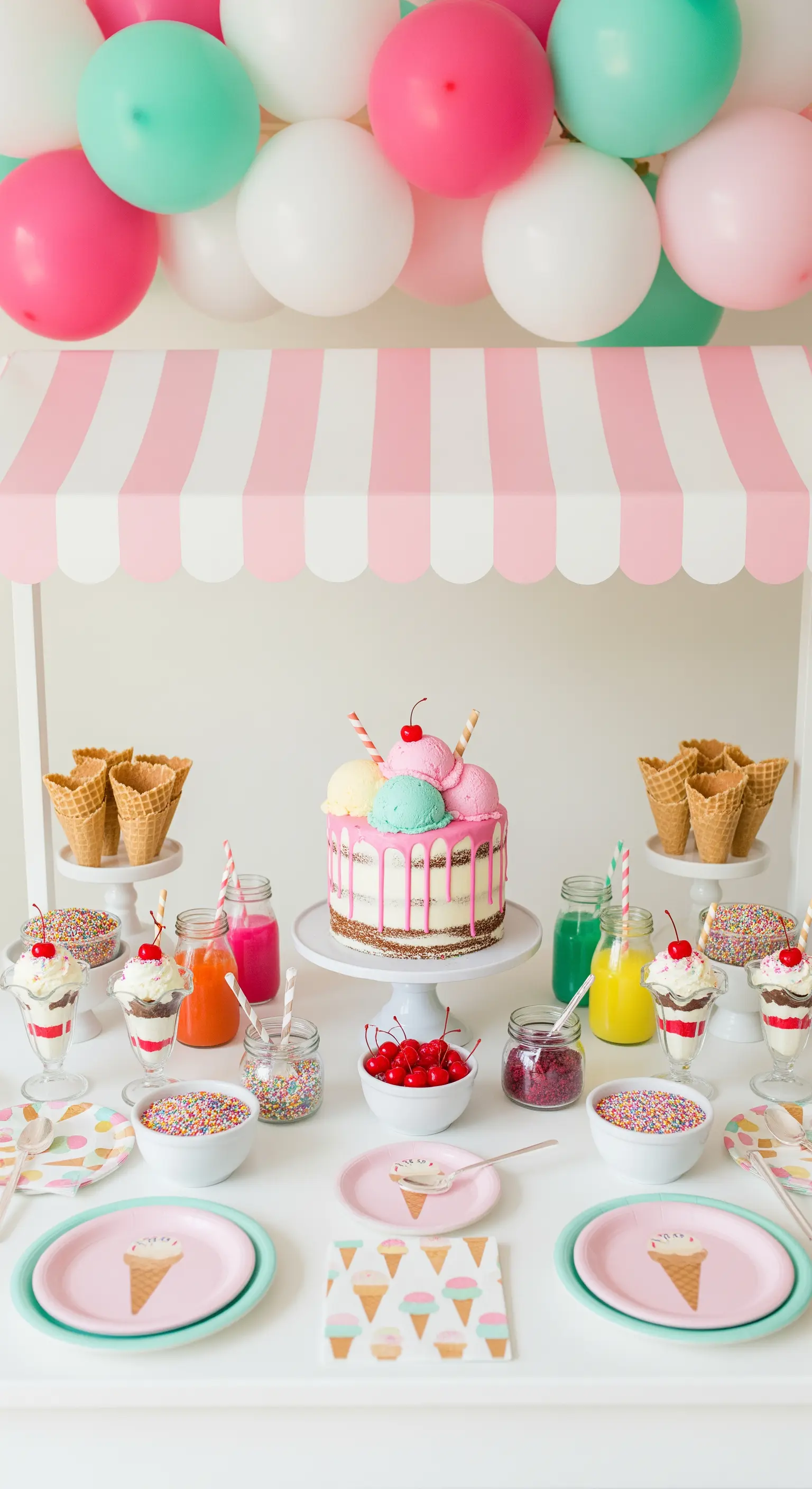 Angolo gelateria con torta drip, coni, coppette e una tenda a righe rosa e bianche.