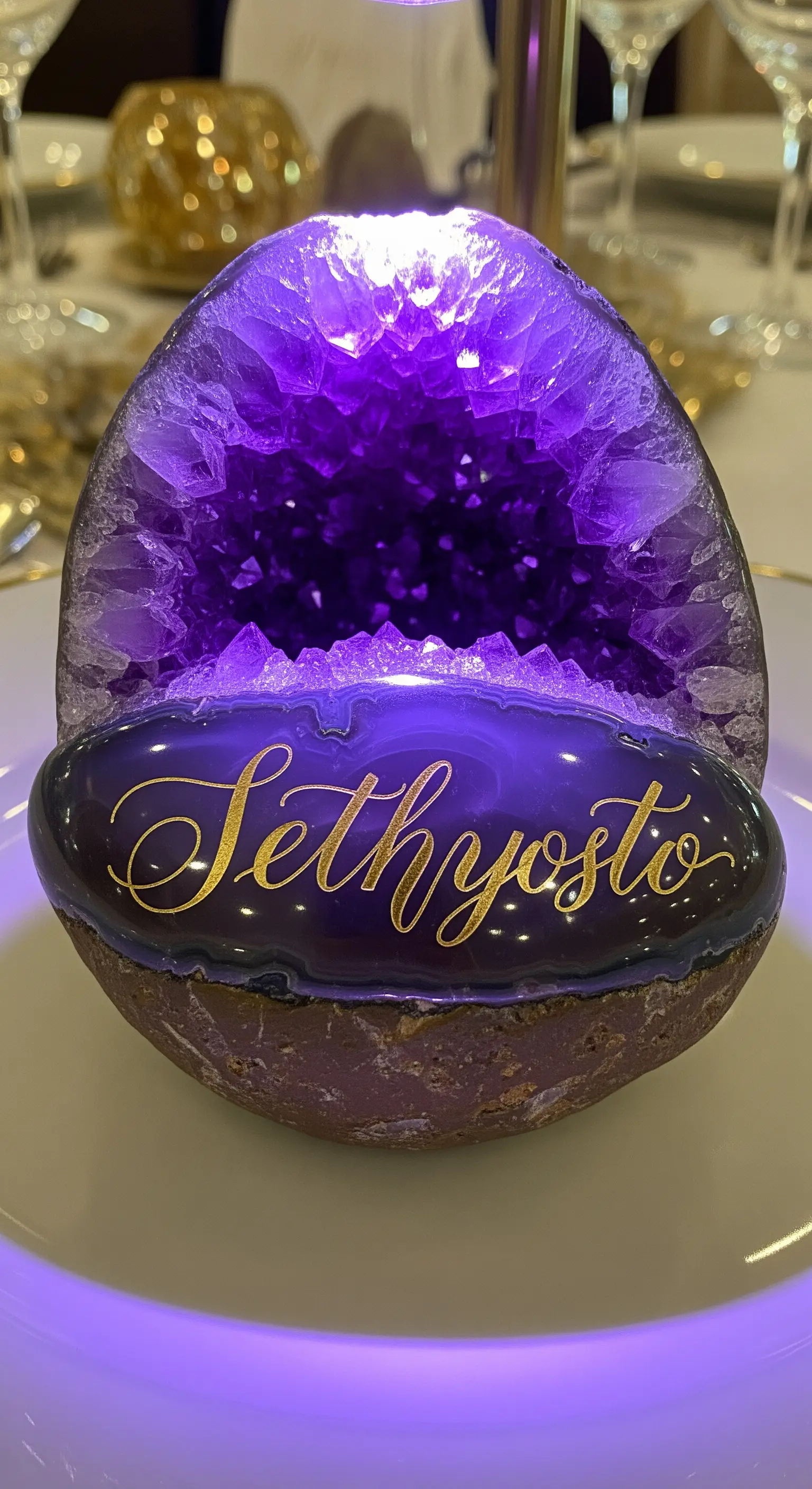 Geode di ametista illuminato dall'interno con un nome scritto in oro sulla base levigata.