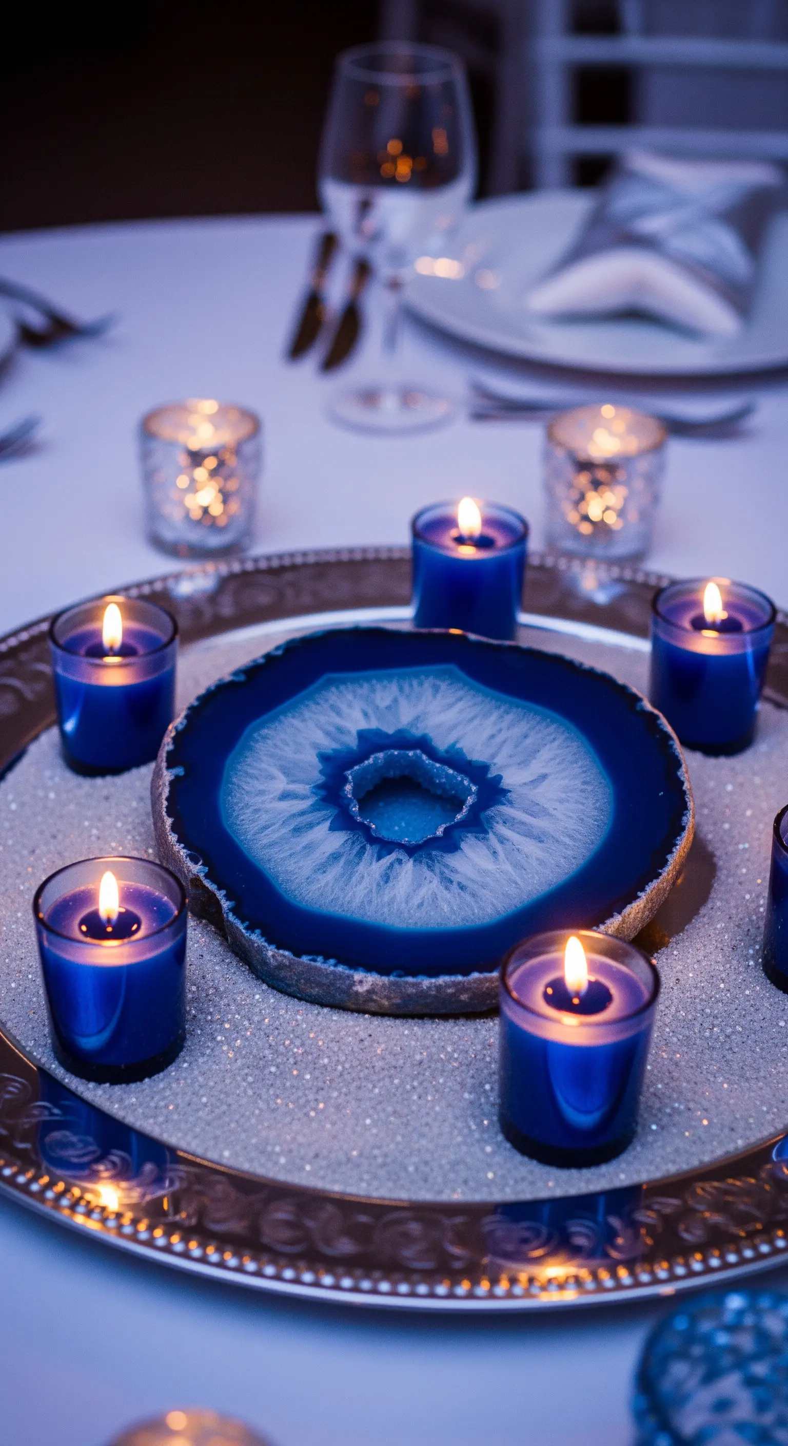 Centrotavola con fetta di agata blu su un vassoio argentato, circondata da candele blu.