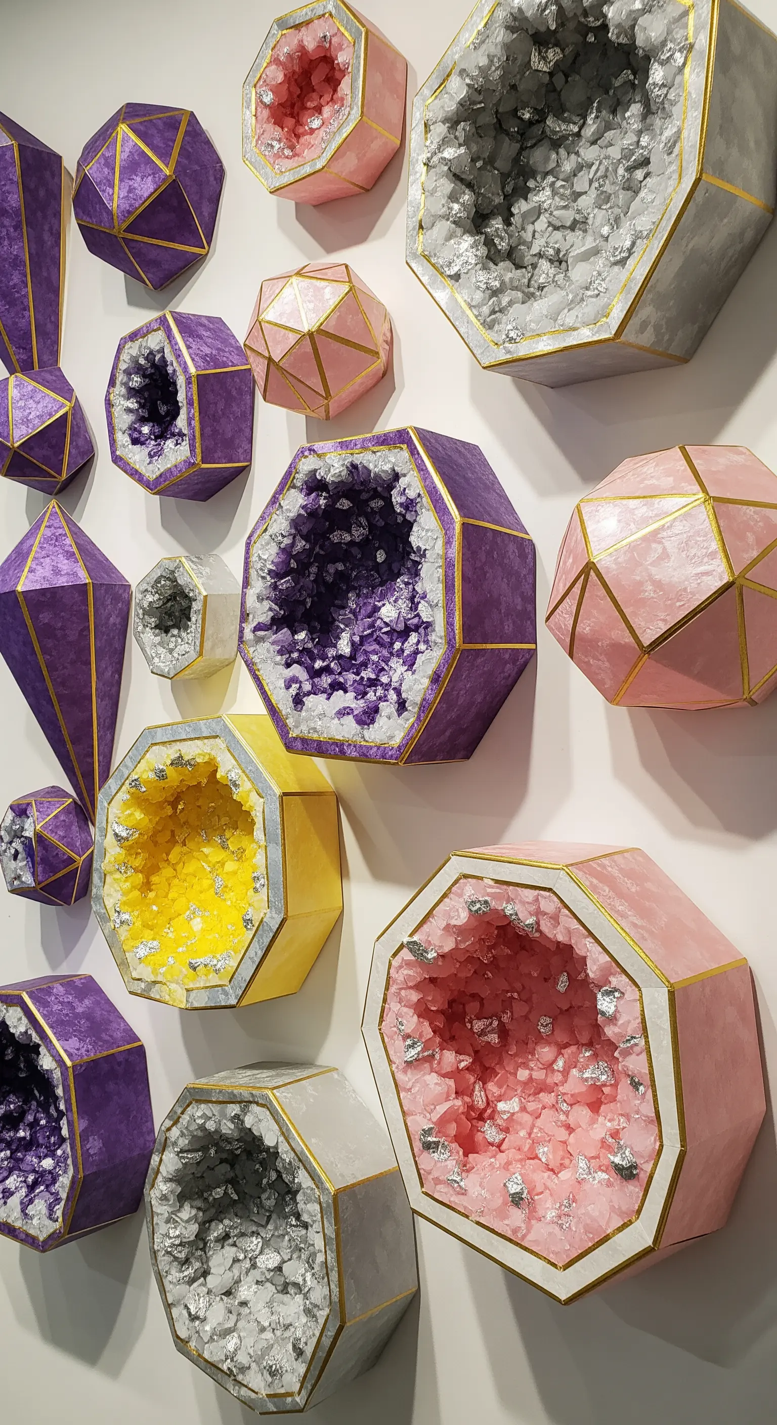 Decorazioni murali a forma di geodi di carta, con esterno colorato e interno ricoperto di glitter.