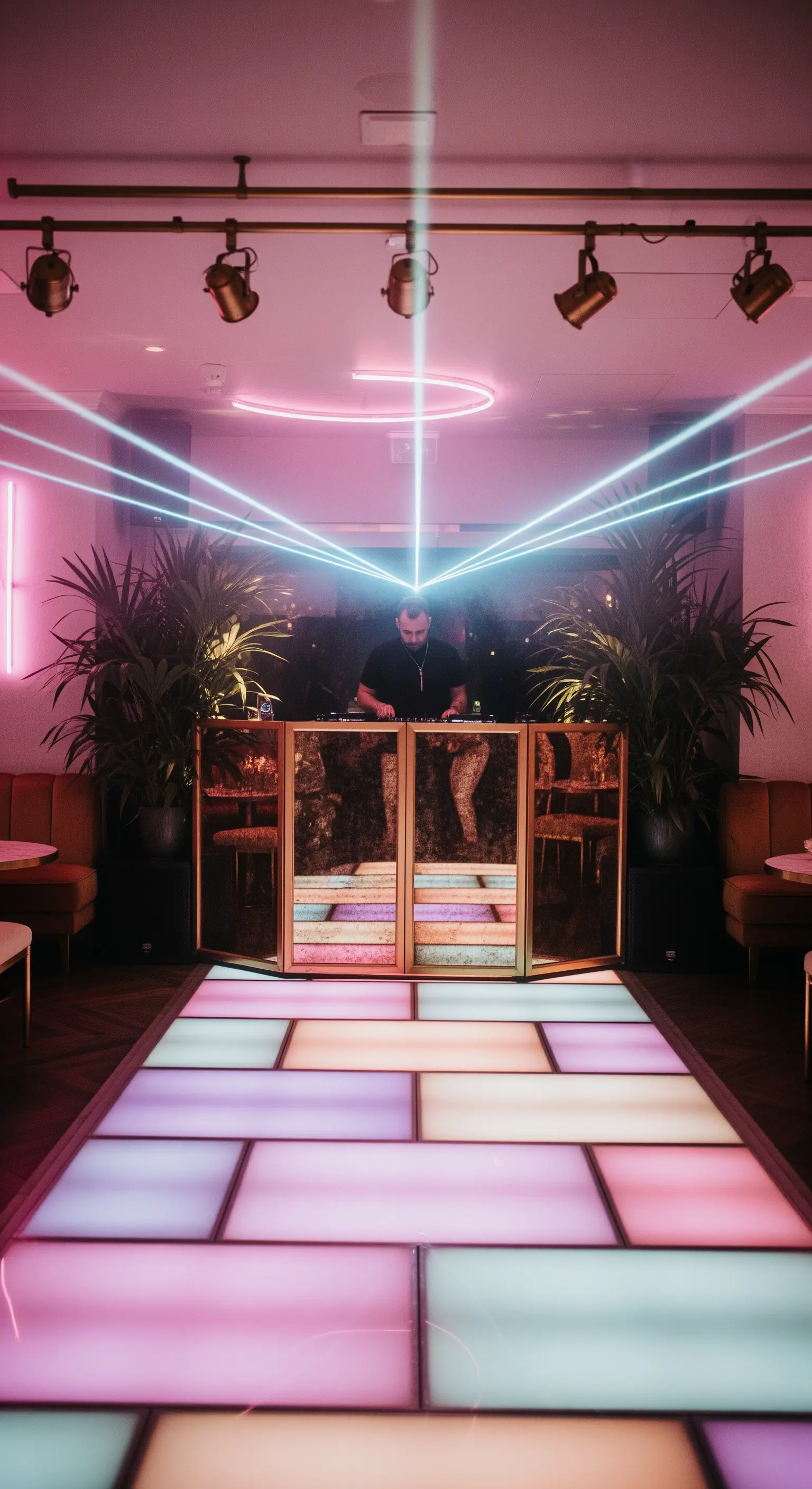 Pista da ballo a LED colorati e DJ booth dorato con laser che si incrociano.