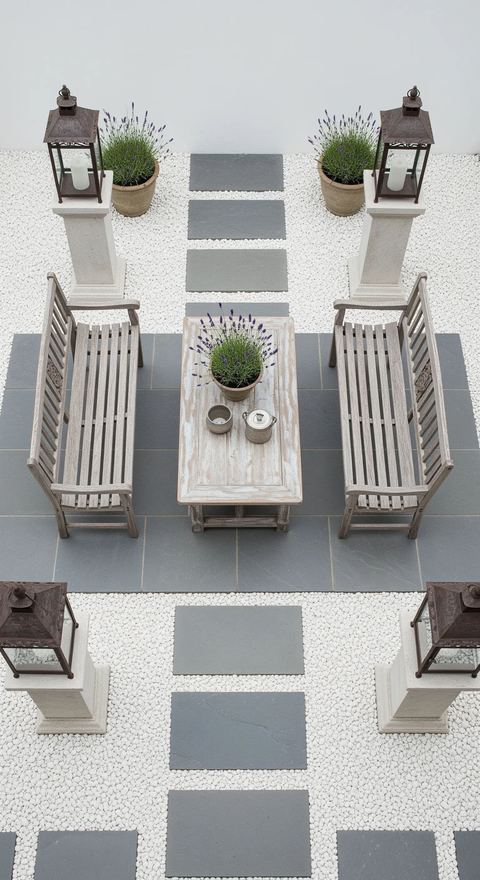 Patio minimalista con ghiaia bianca, lastre di pietra grigia e arredi in legno decapato.