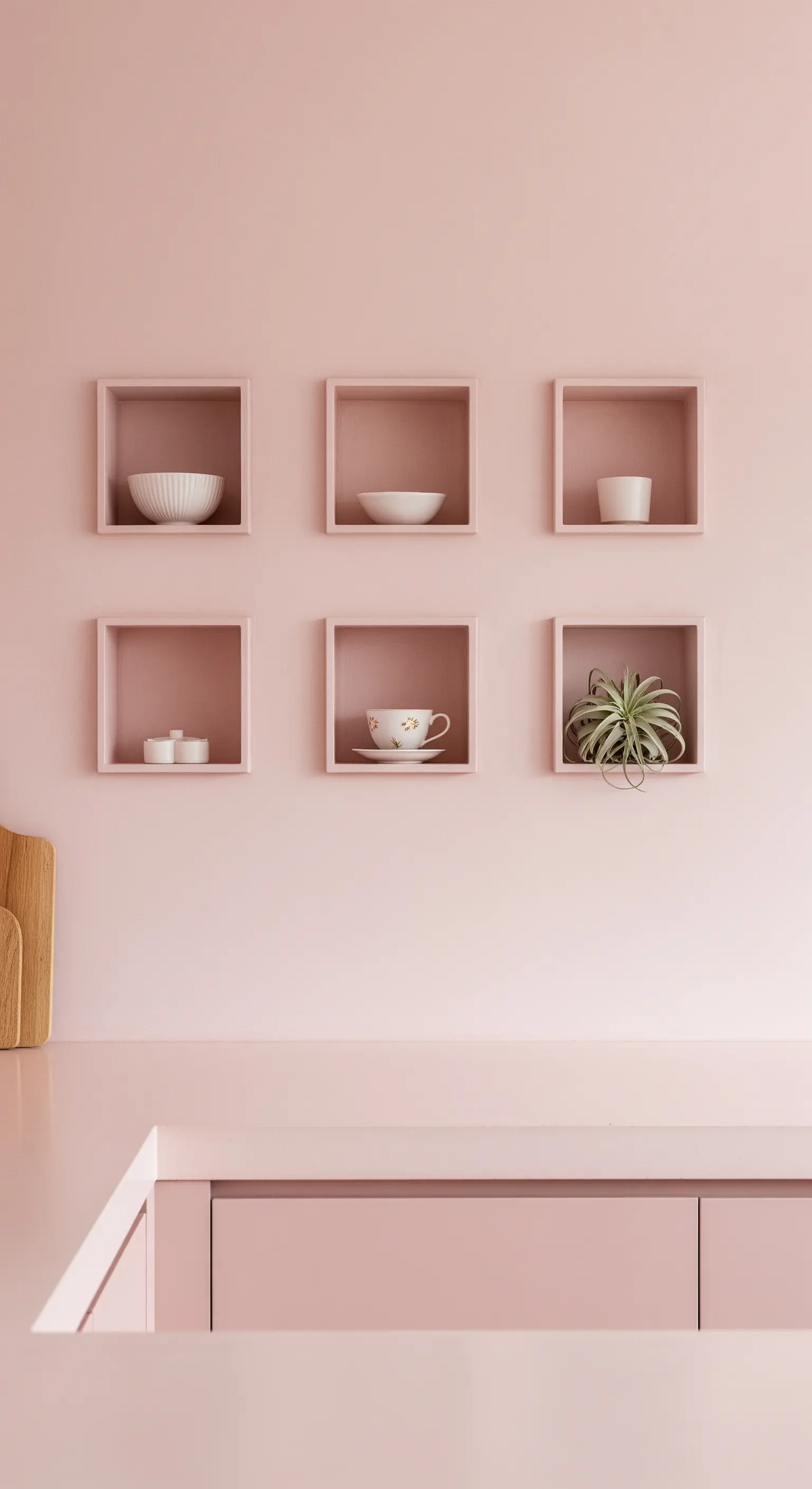 Sei mensole a cubo rosa su una parete rosa, con piccoli oggetti di ceramica.