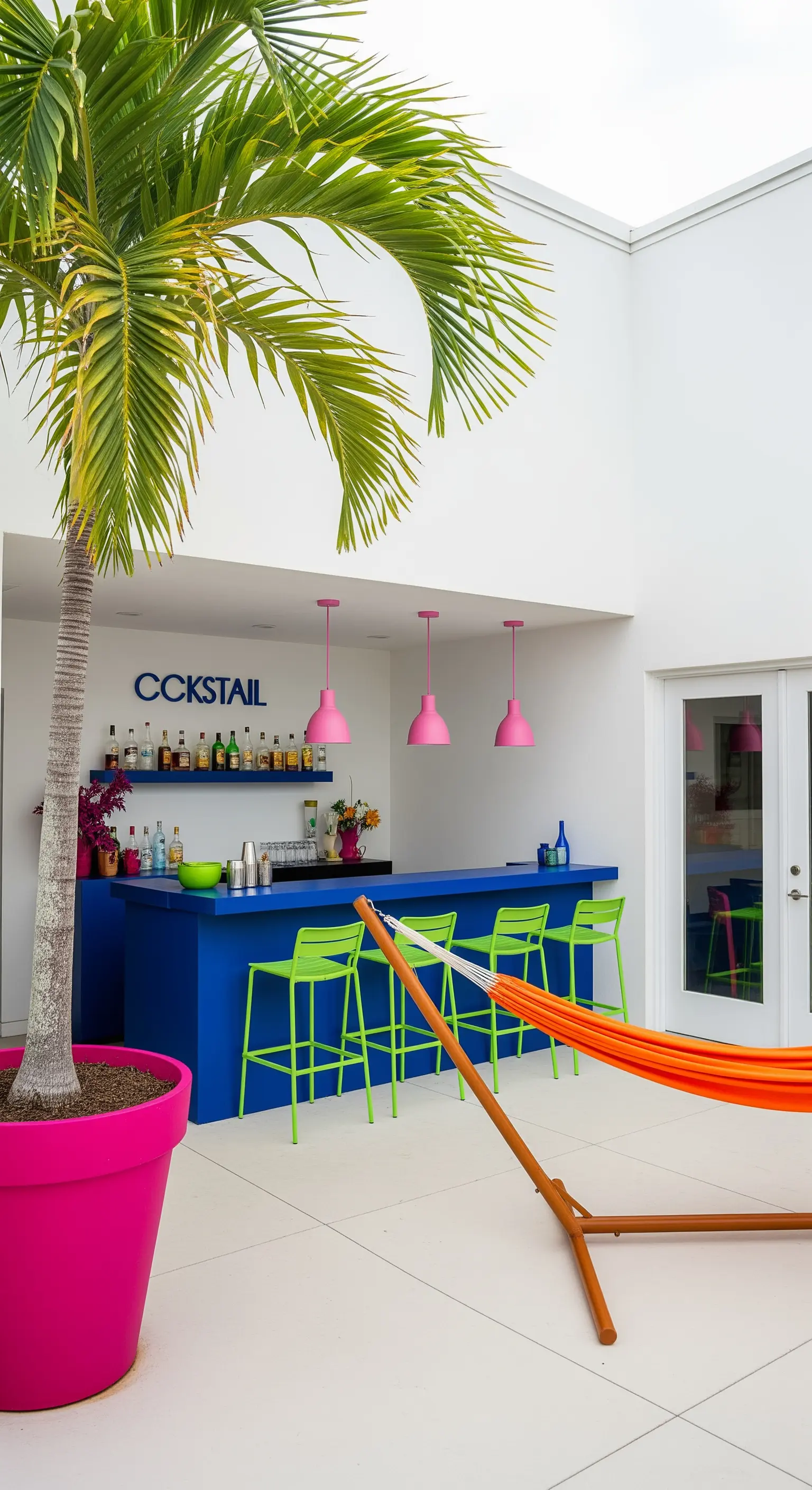 Patio minimalista con bar blu elettrico, sgabelli verdi, lampade rosa e amaca arancione.