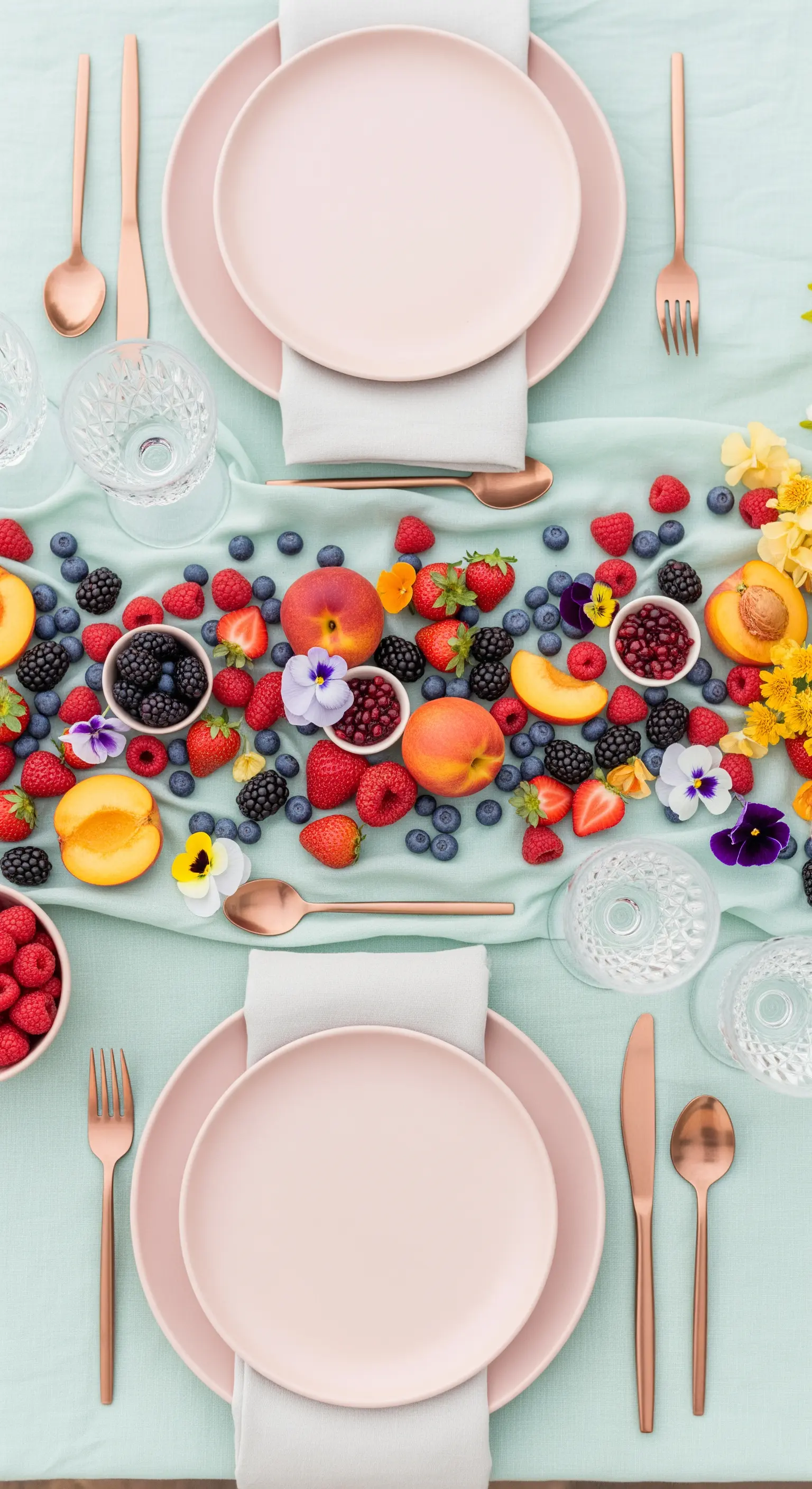 Tavola pastello con frutti di bosco sparsi su un runner verde menta.