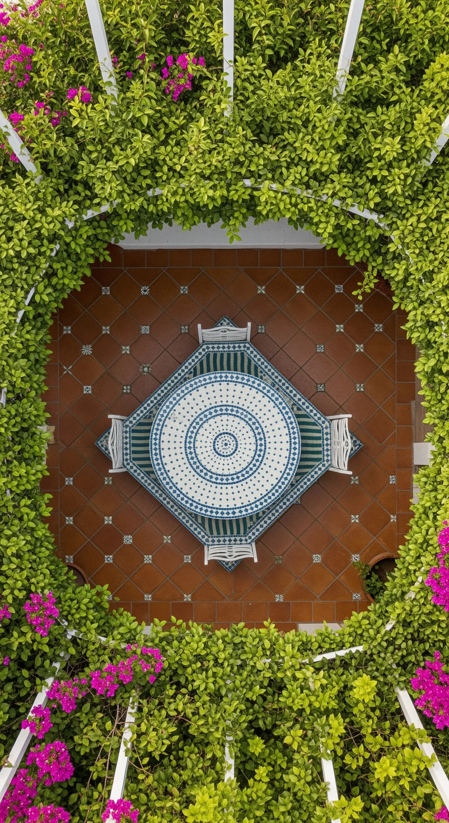 Vista dall'alto di un tavolo rotondo in mosaico sotto una pergola quadrata ricoperta di verde