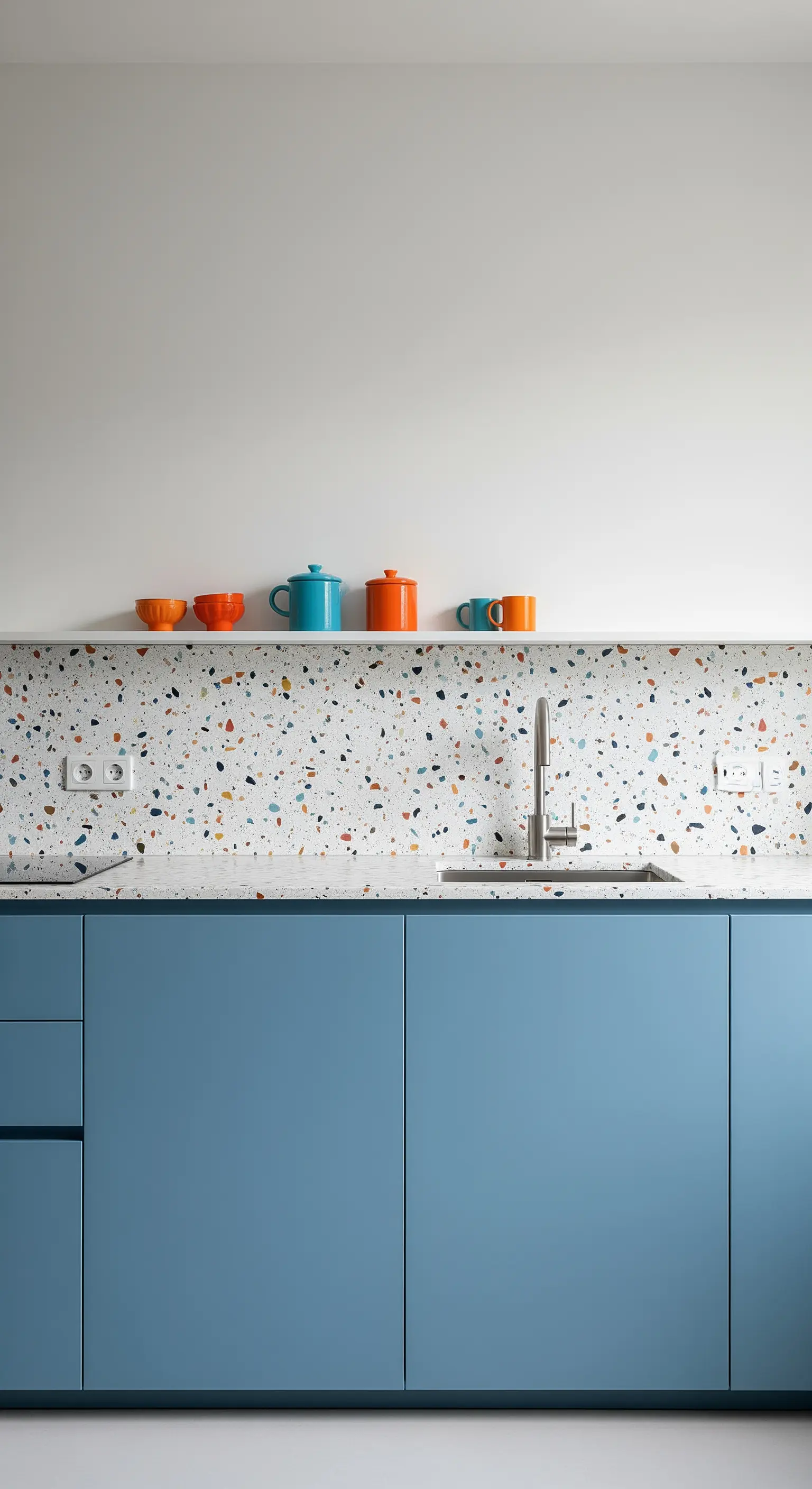 Cucina con mobili blu e paraschizzi in terrazzo con scaglie multicolore.