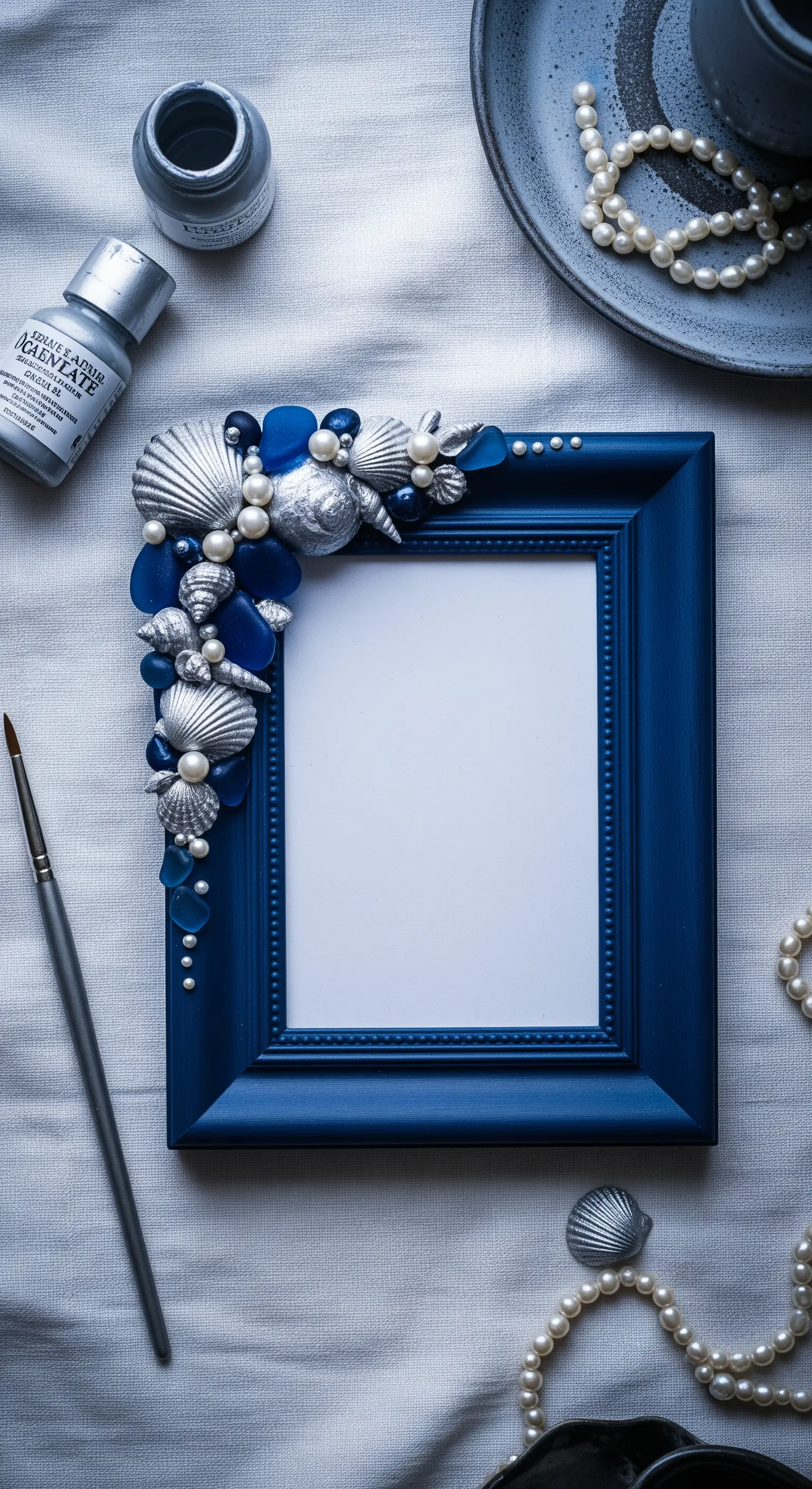 Angolo di una cornice blu decorato con conchiglie argentate, perle e vetri di mare blu.